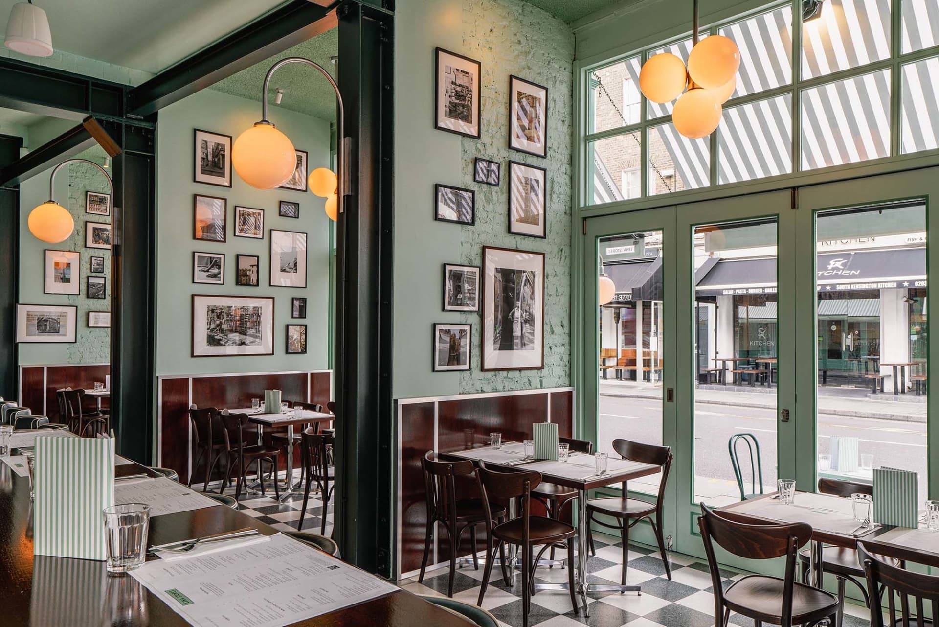 A restaurant interior with green walls, checkered floors, and various seating arrangements, creating a cozy atmosphere for guests