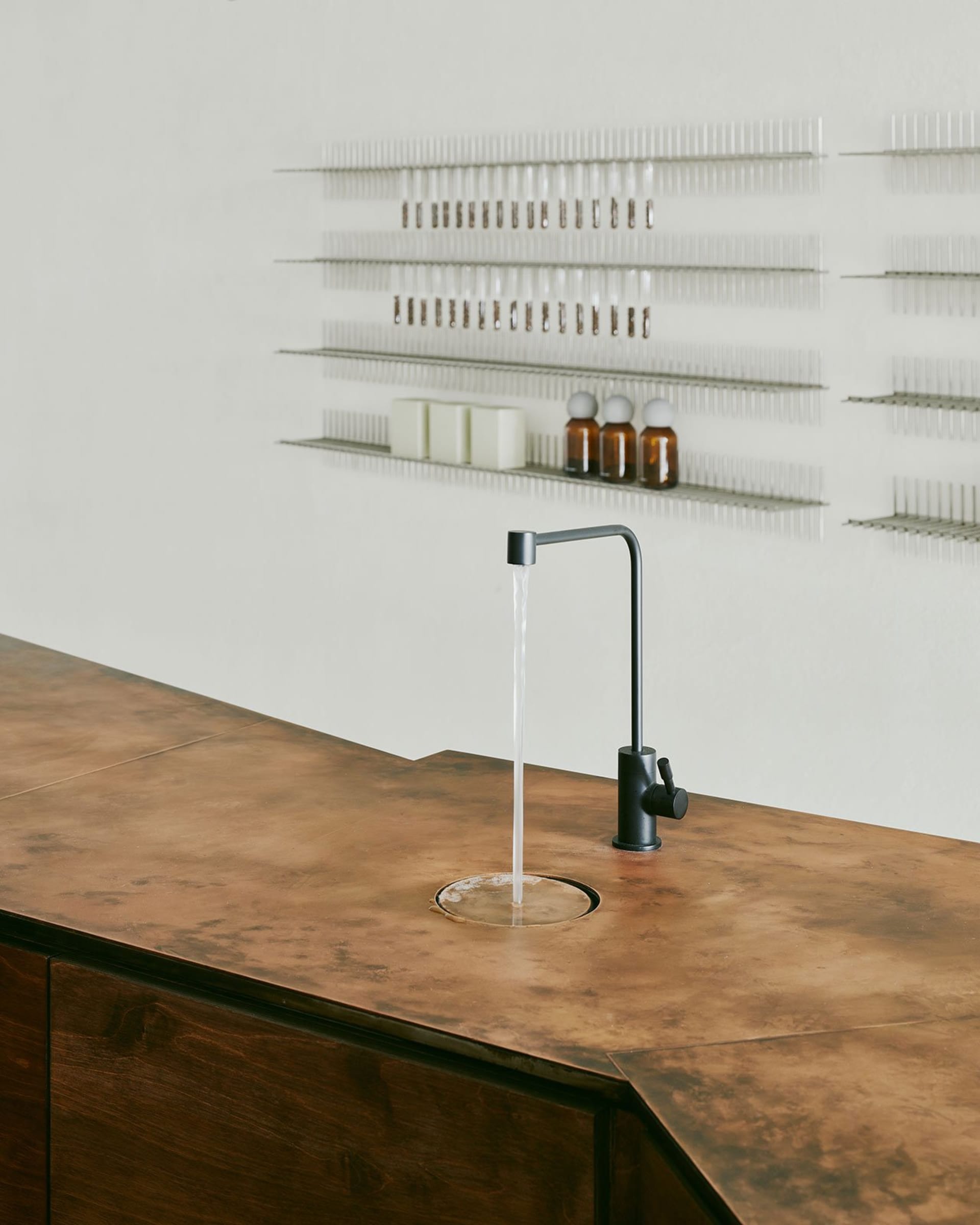 A clean and organized kitchen counter with a faucet and several bottles placed around it
