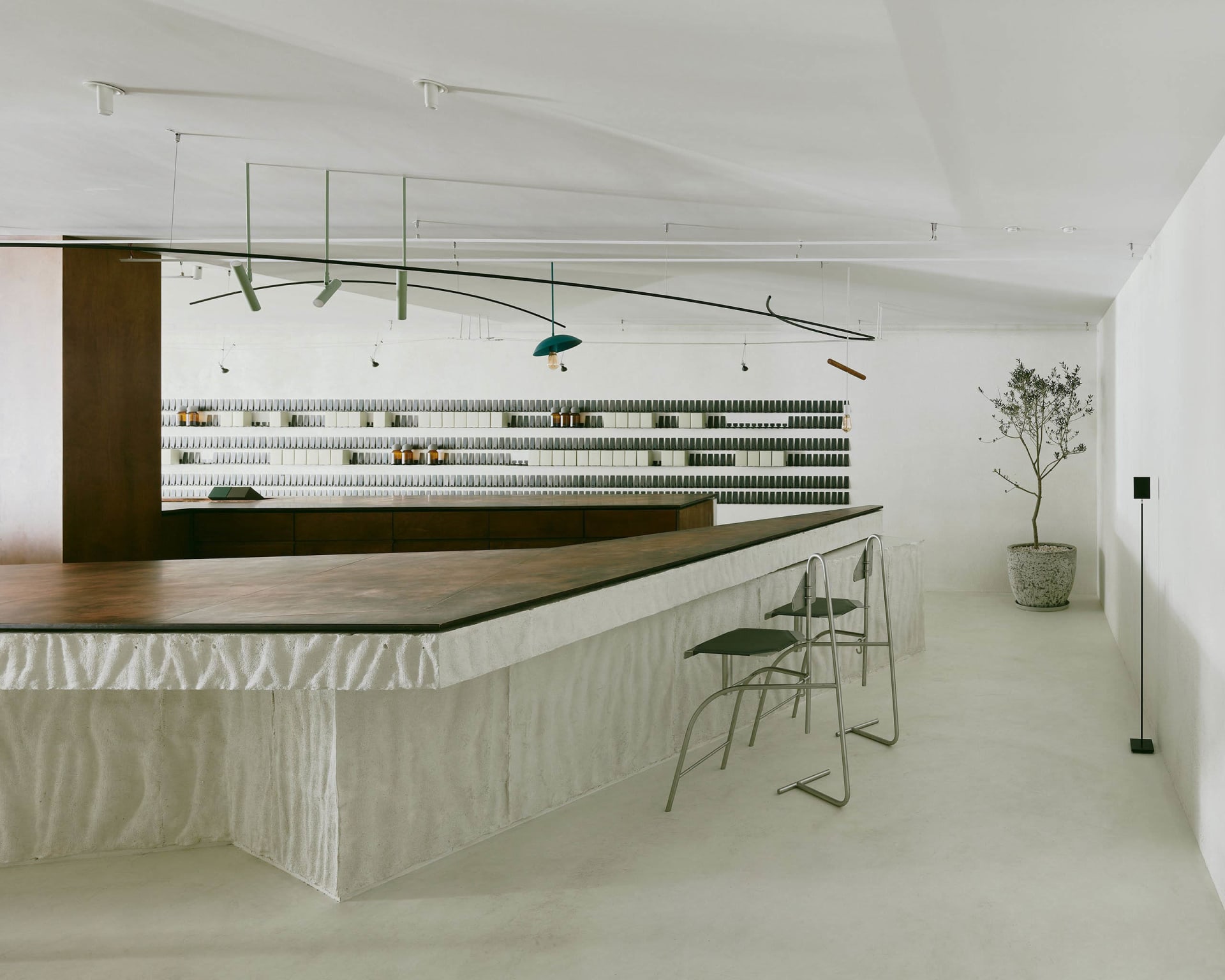 A modern bar area with a wooden countertop and metal chairs, featuring multiple bottles on display in a clean and well-organized space