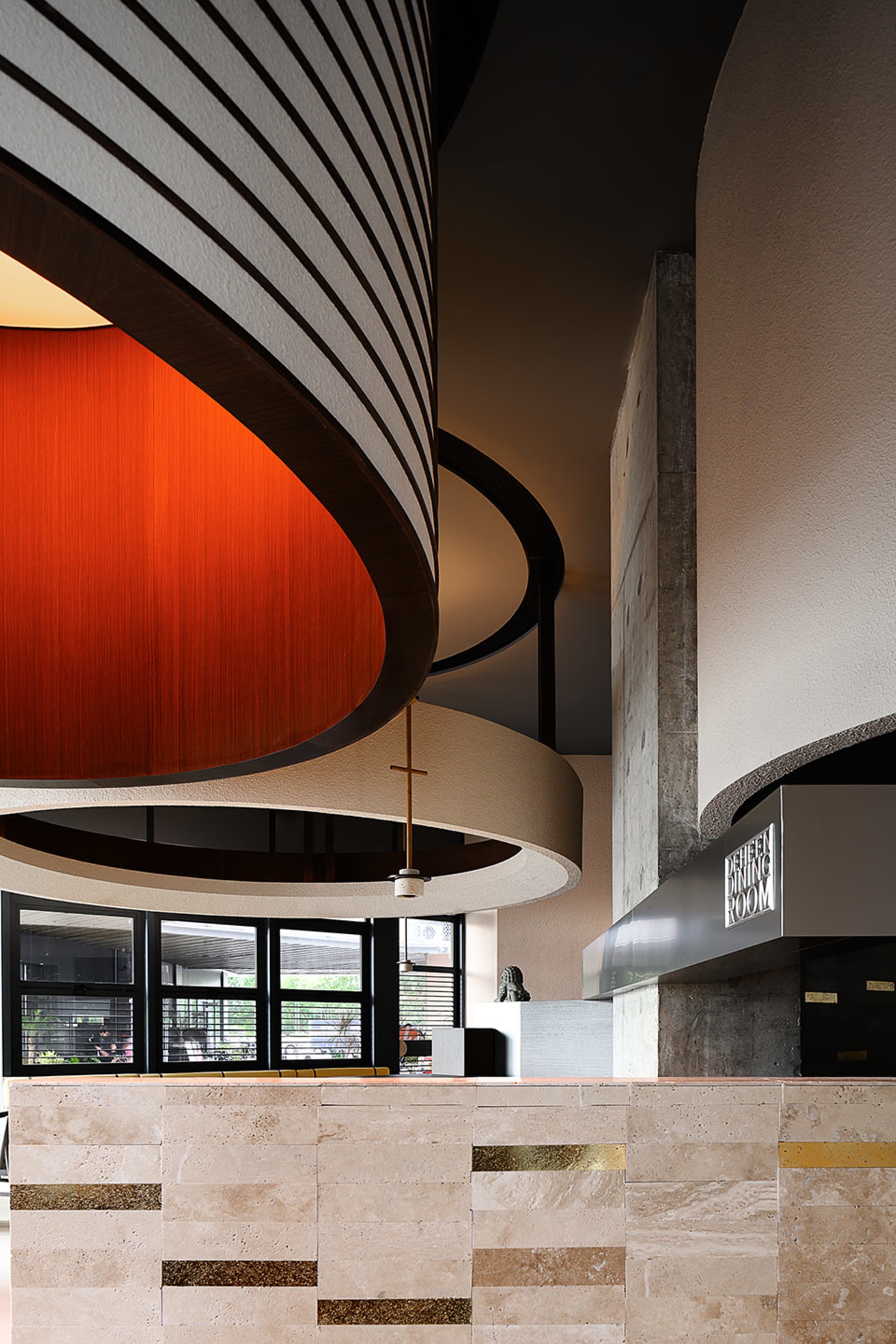 A modern lobby with a circular structure, dome ceiling, and a combination of wood and concrete walls, with natural light from multiple windows
