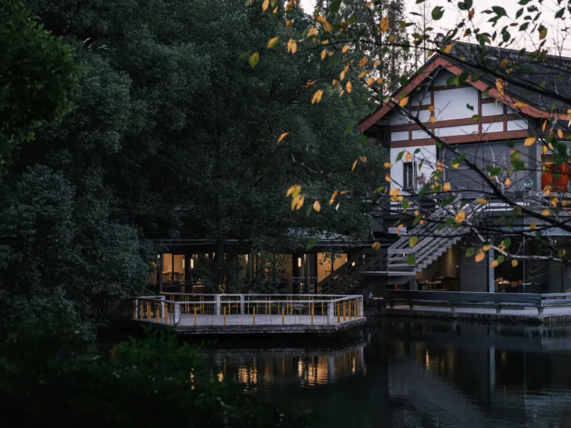 A yellow building near water with a staircase and outdoor seating area