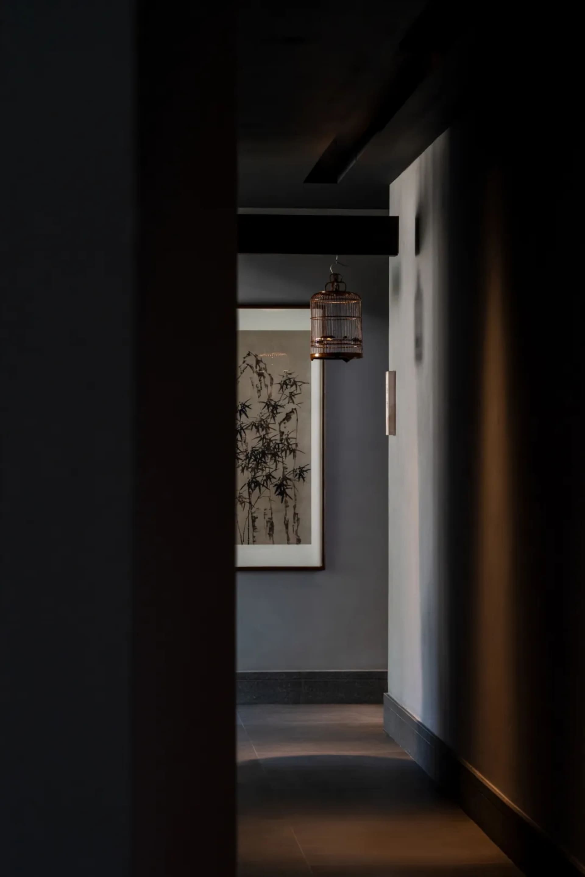 A dimly lit hallway with a gray wall, a doorway, and two framed pictures on display