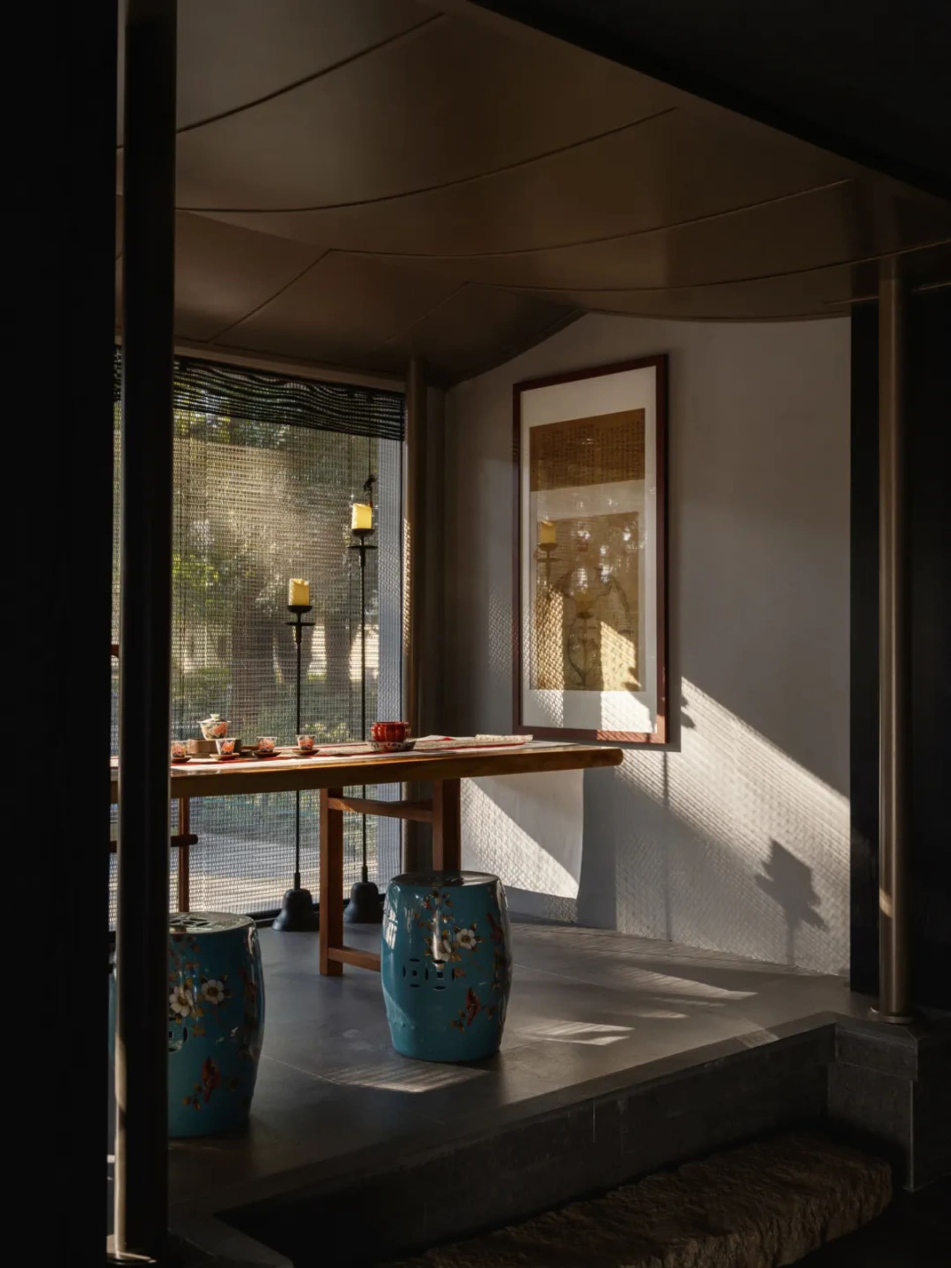 Dining space with Asian-inspired decor, a blue vase, and a potted plant, surrounded by chairs in a warm and inviting atmosphere
