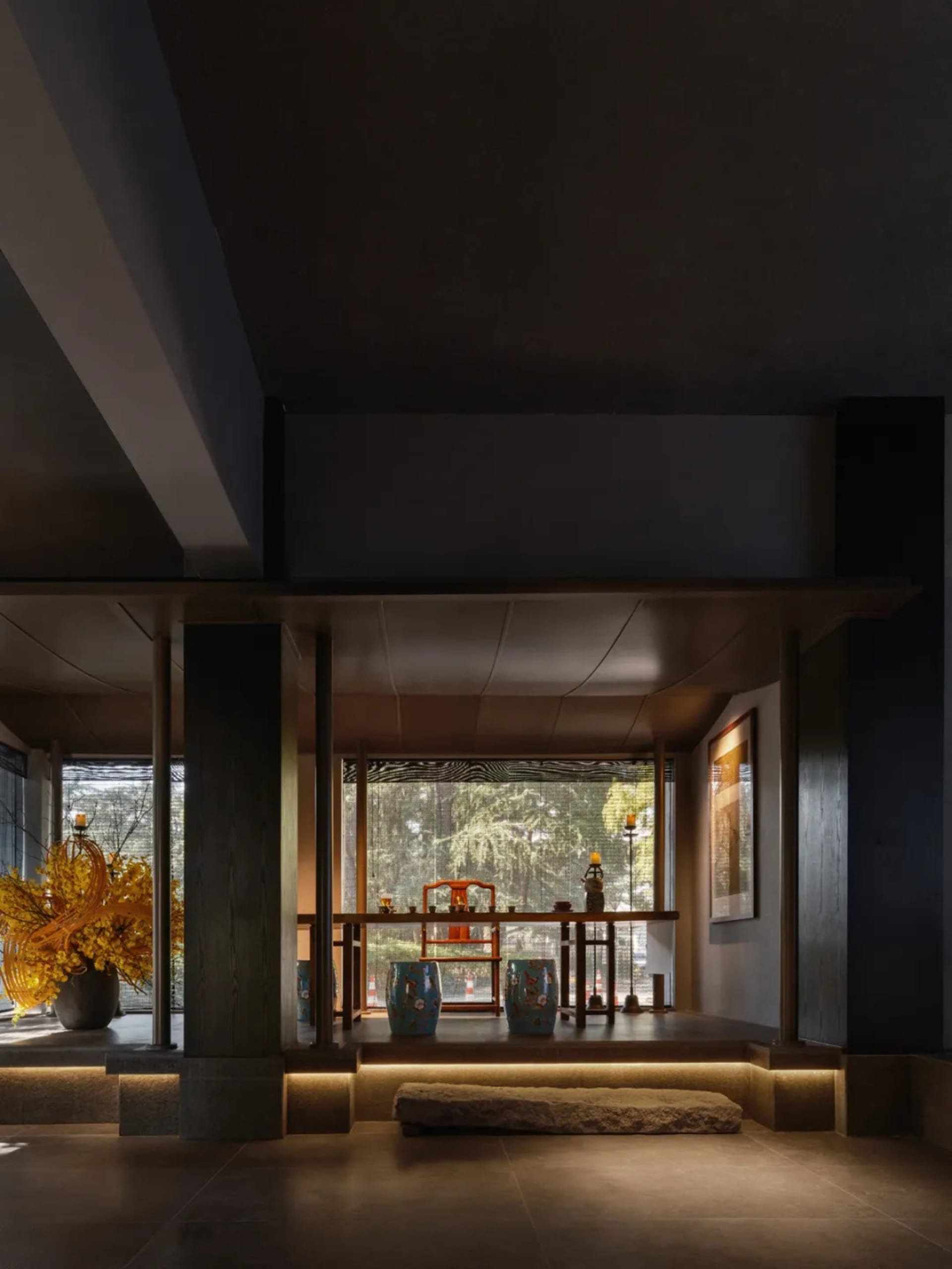 A modern dining room with a black and white color scheme, wooden elements, and a well-lit atmosphere, featuring a dining table and chairs with vases on the table