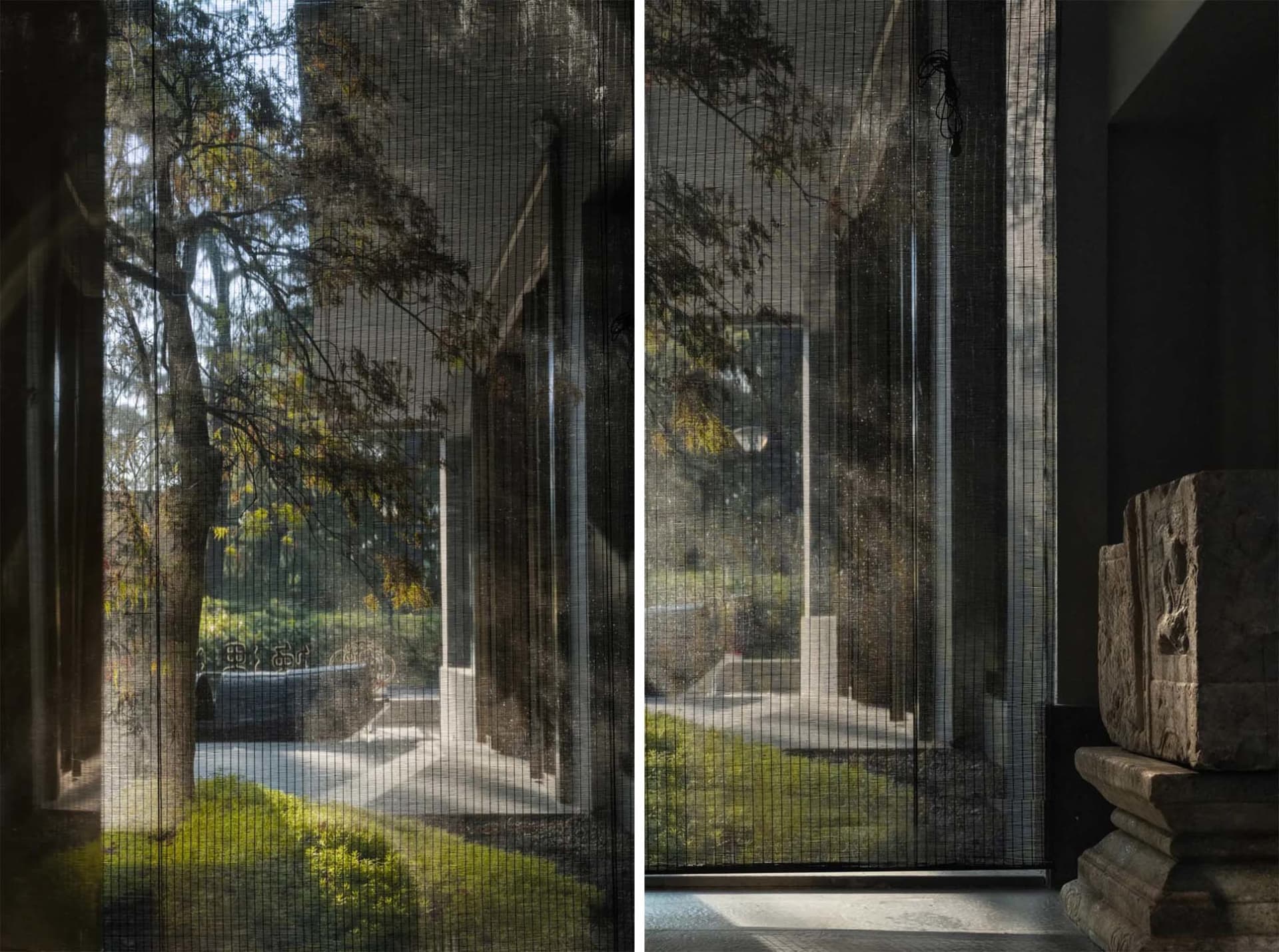 A house with a calm atmosphere, featuring large windows with blinds and a smaller window with curtains, and a bench near the windows, surrounded by trees and sunlight