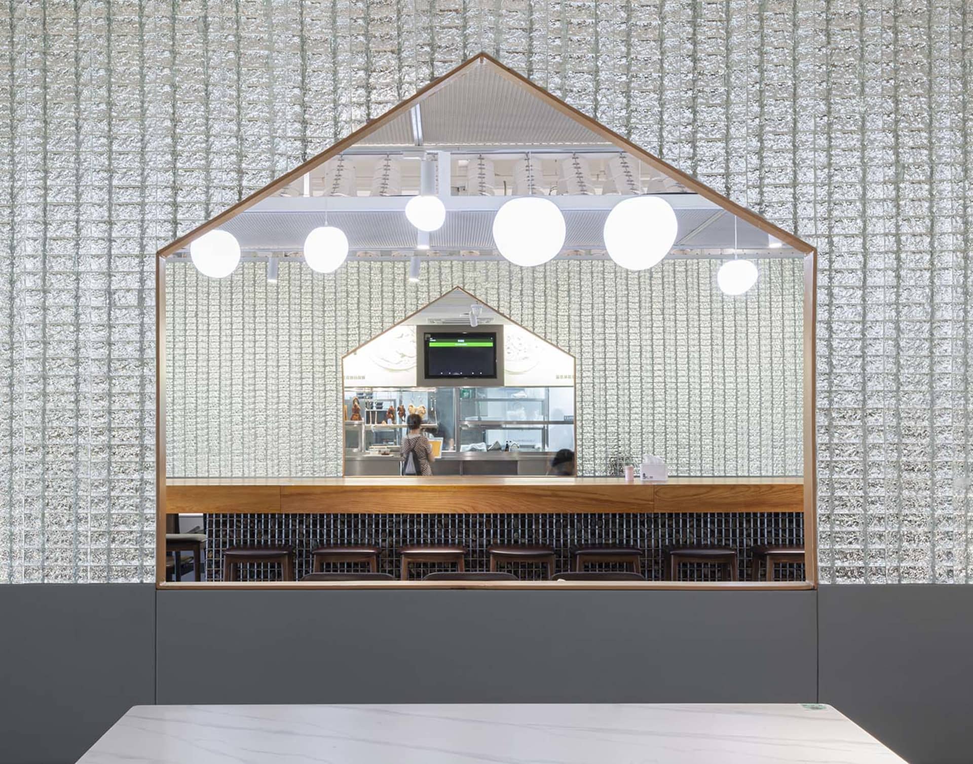 Modern restaurant bar with wood accents, TVs, and comfortable seating, well-lit for a welcoming atmosphere