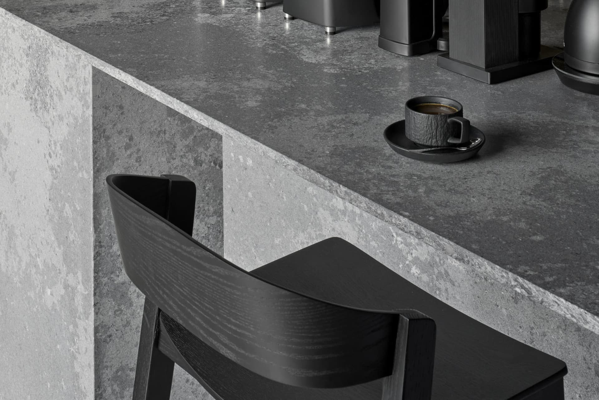 Industrial kitchen with a countertop, coffee pots, and chairs, conveying a functional and practical atmosphere
