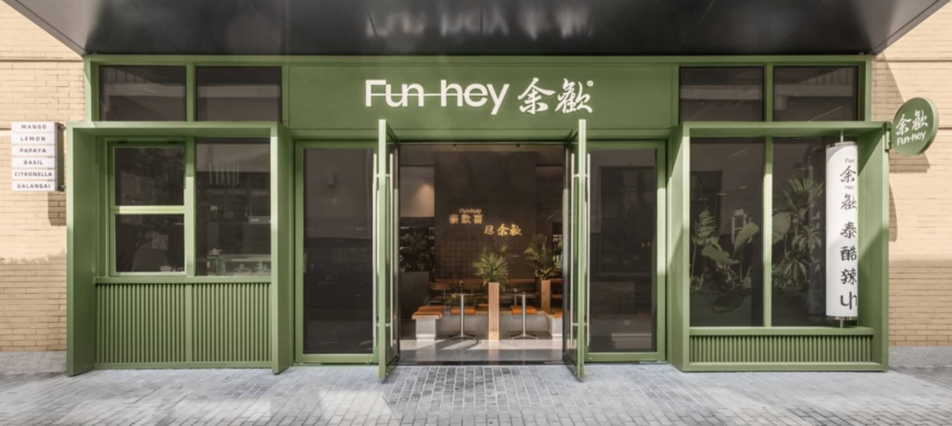 An inviting Asian restaurant with green walls, wooden furniture, and potted plants, creating a comfortable dining atmosphere