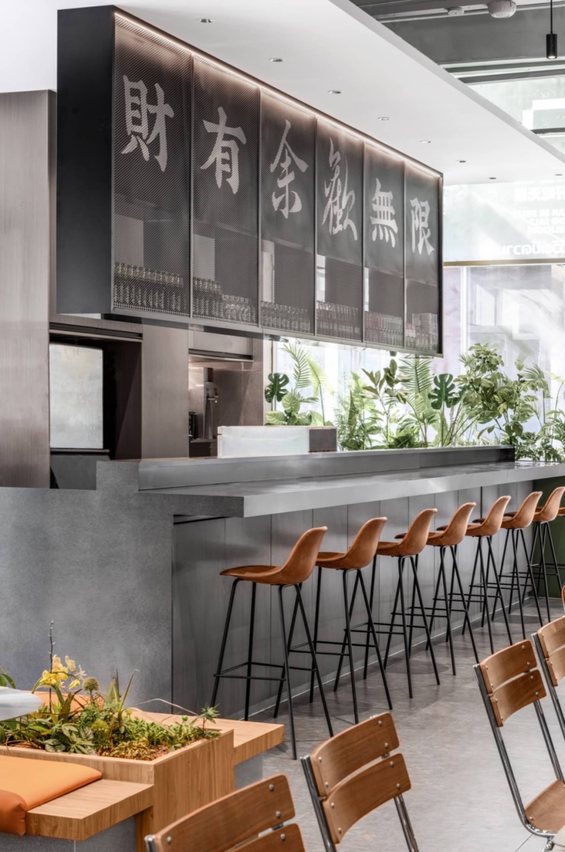 A modern Asian restaurant interior with a long metal counter and multiple chairs, gray and black elements, and a sleek atmosphere