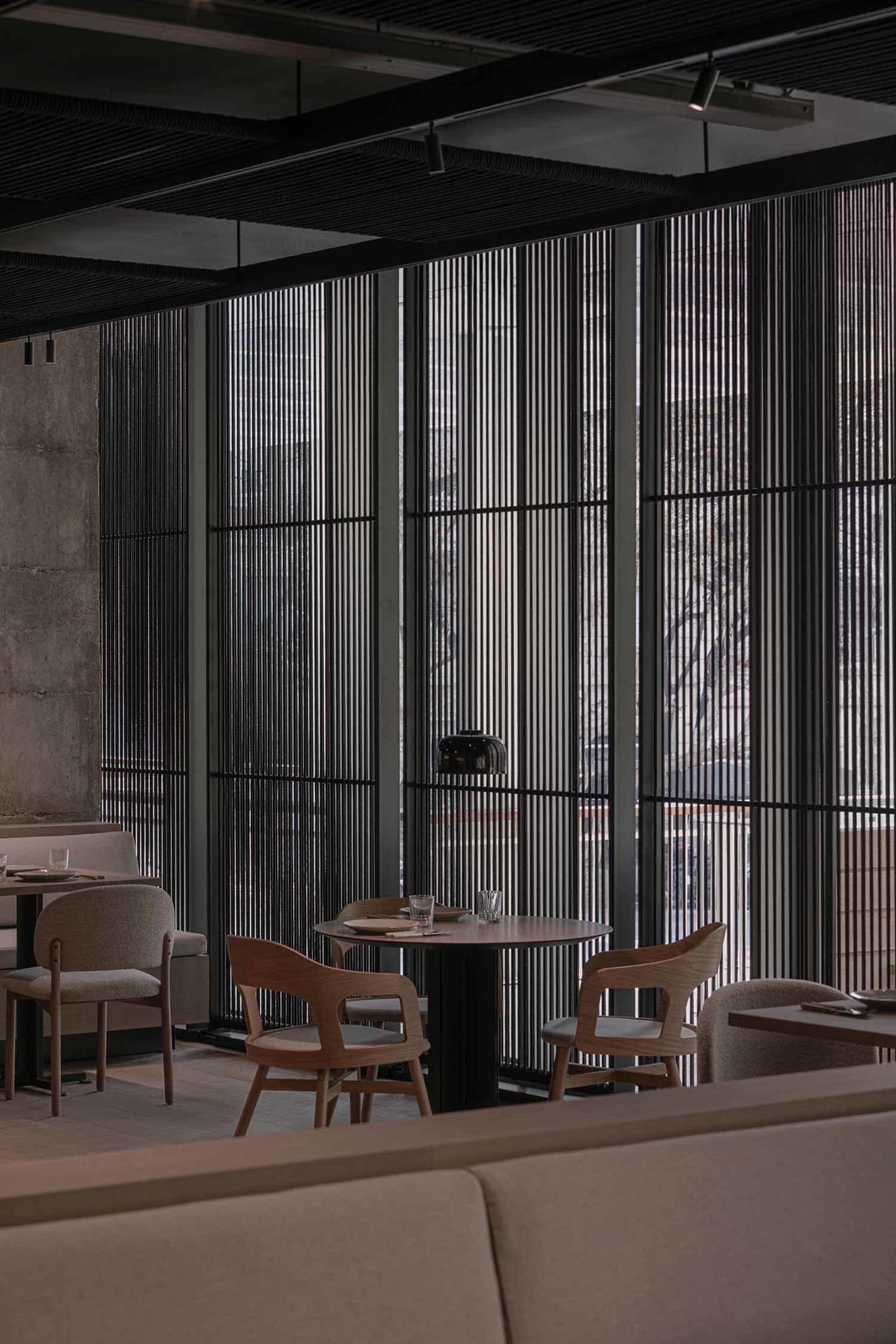 A modern restaurant interior with a dining area featuring multiple tables and chairs, wood furniture, and a welcoming atmosphere