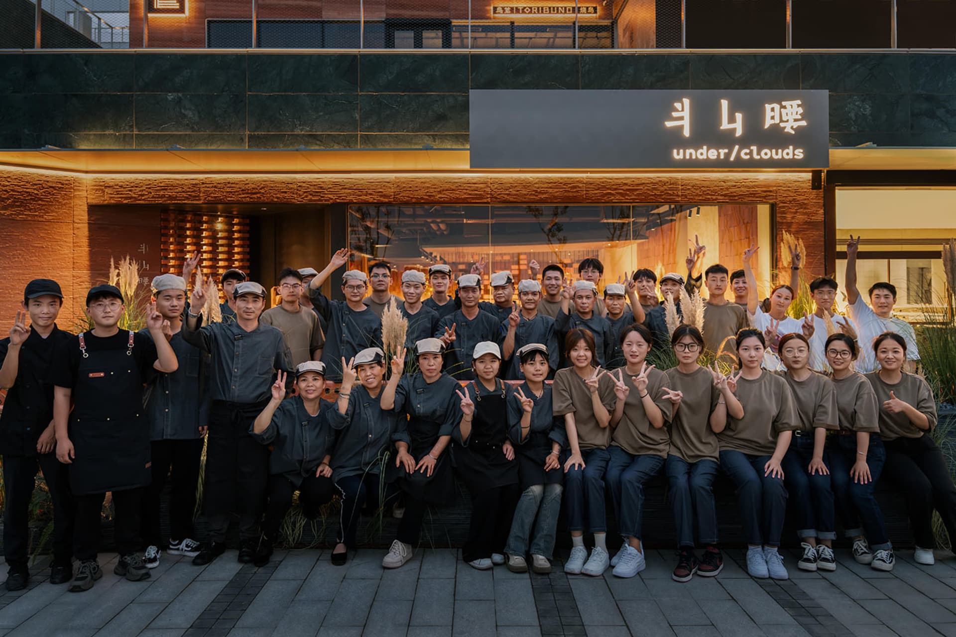 A group of people gathered in front of an Asian-themed restaurant, smiling and posing for a photo
