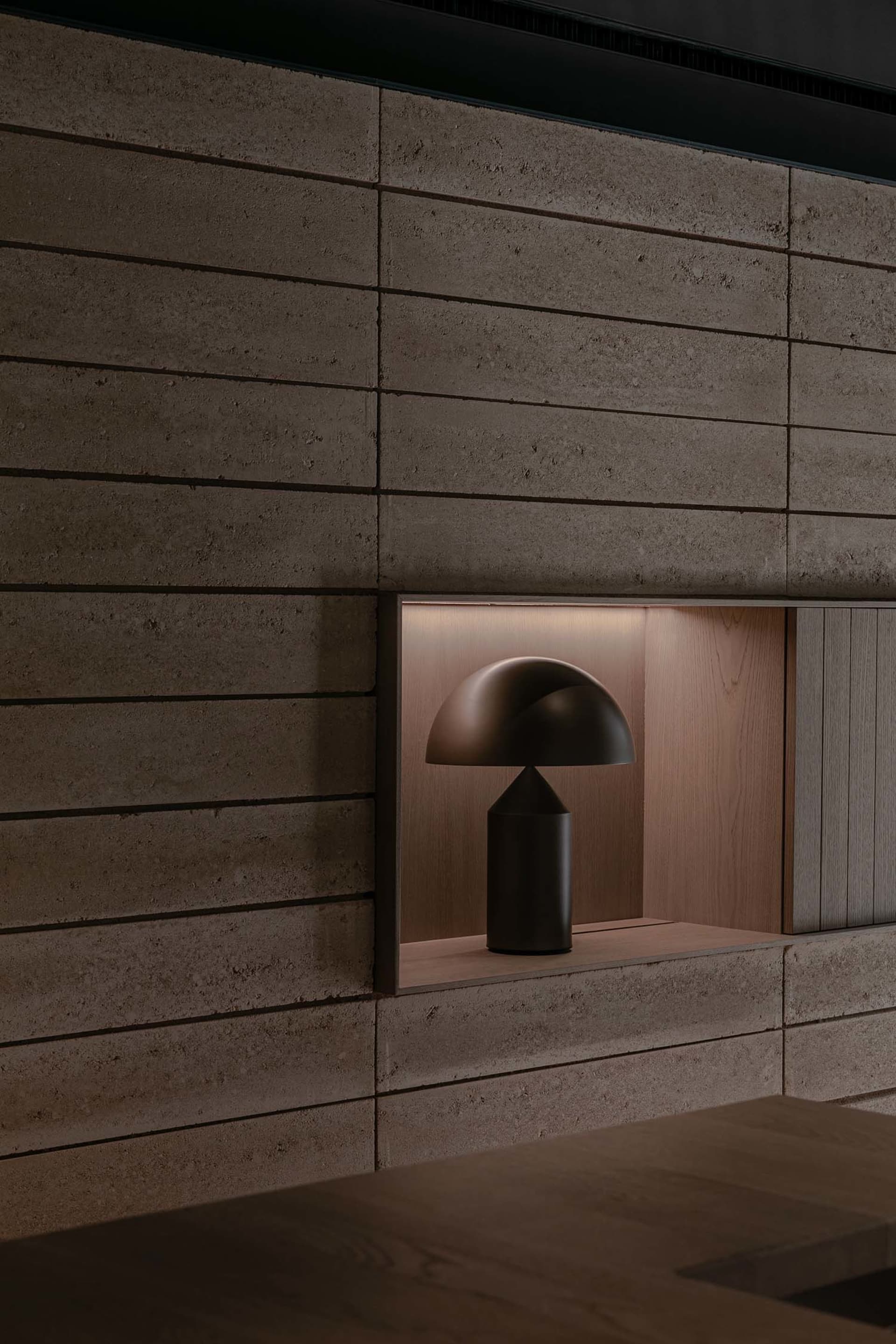 A cozy living space with a wooden table and a lamp with a black base and white shade, set against a darker background