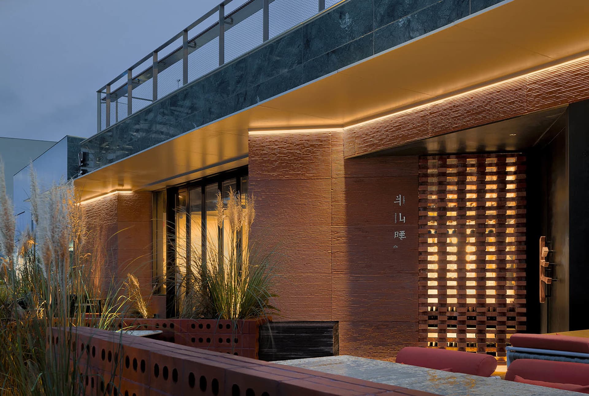 A cozy brick house with a balcony and potted plants, set in a warm and inviting environment