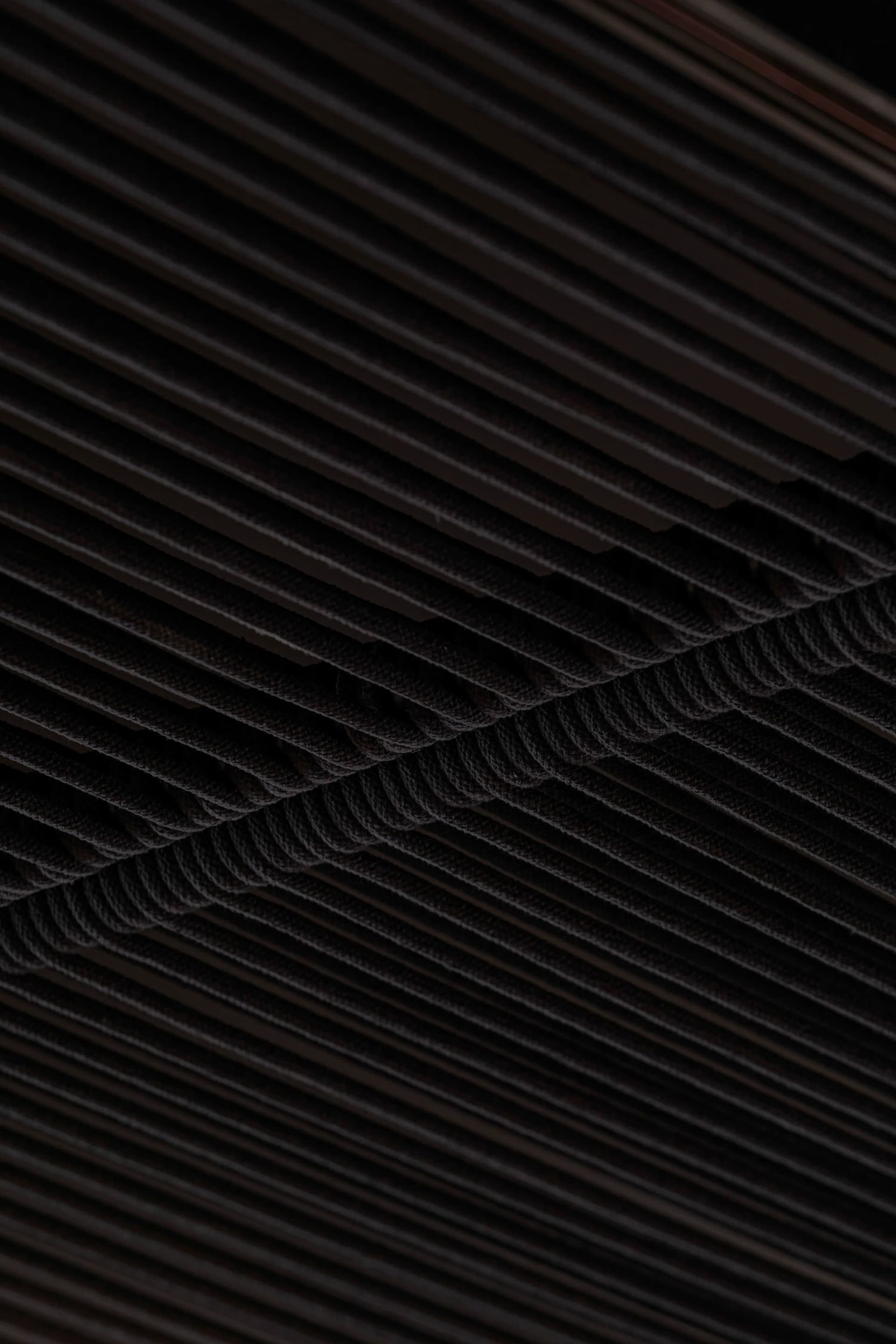 Dark industrial space with a black metal ceiling featuring multiple rows of ropes, creating a striking visual effect