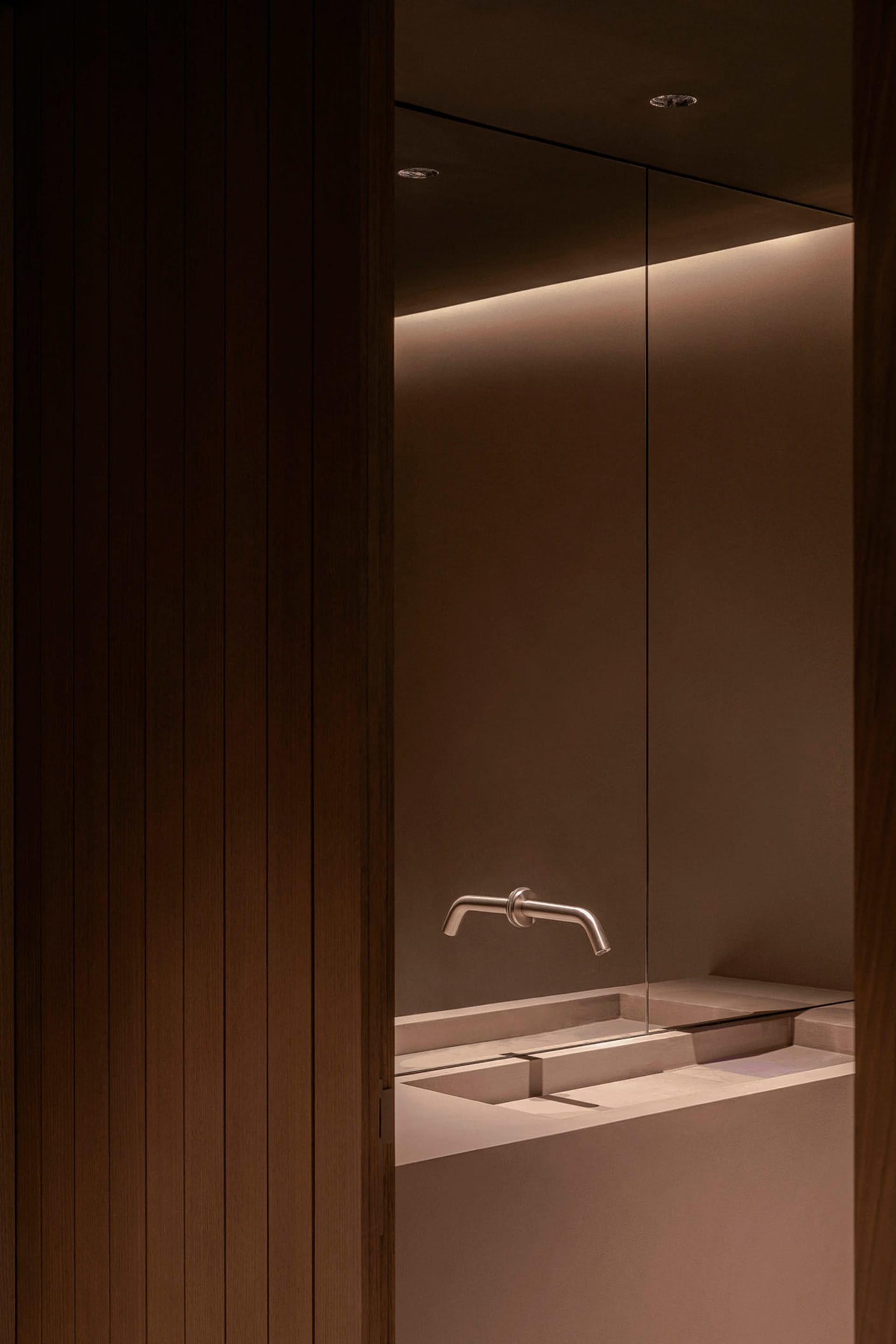 Modern bathroom with a sink and shower area, featuring a wooden wall and minimalist design