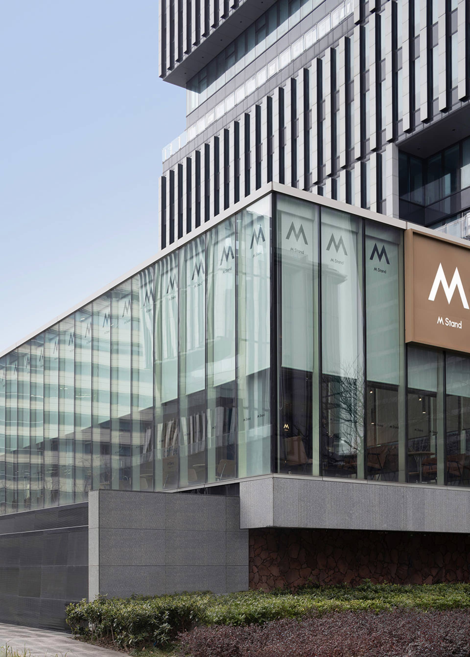 A modern building with a large glass front, showcasing its interior design and allowing natural light to enter the space, creating a bright and inviting atmosphere