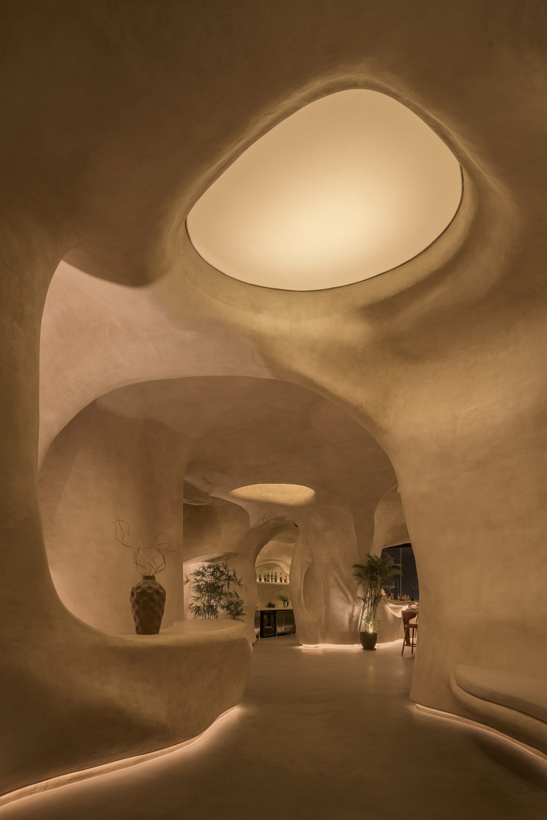A curved hallway with arches connecting multiple rooms, featuring potted plants and vases, blending modern and traditional architectural elements