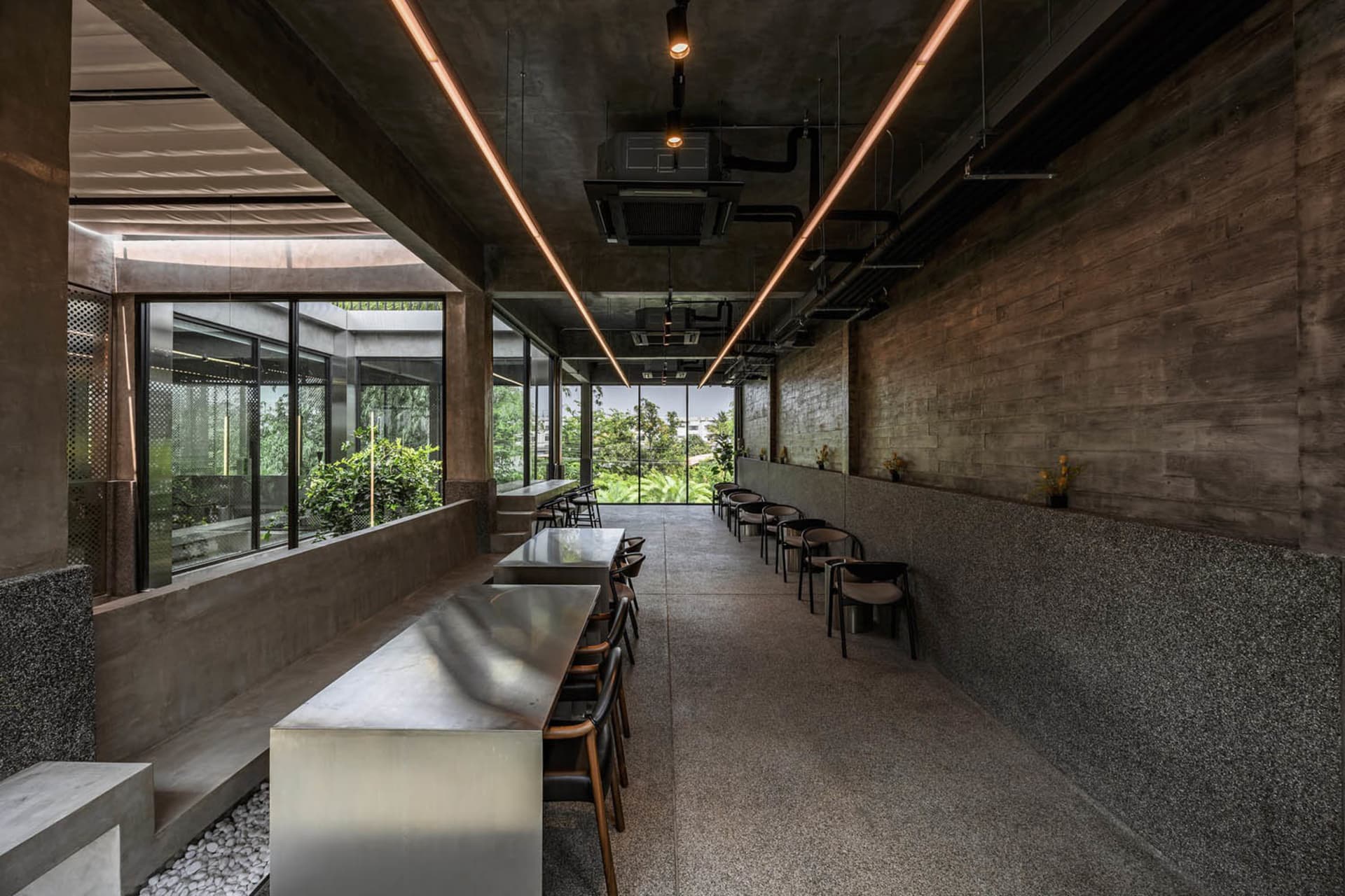 A modern dining area with a large silver table surrounded by chairs, well-lit and inviting
