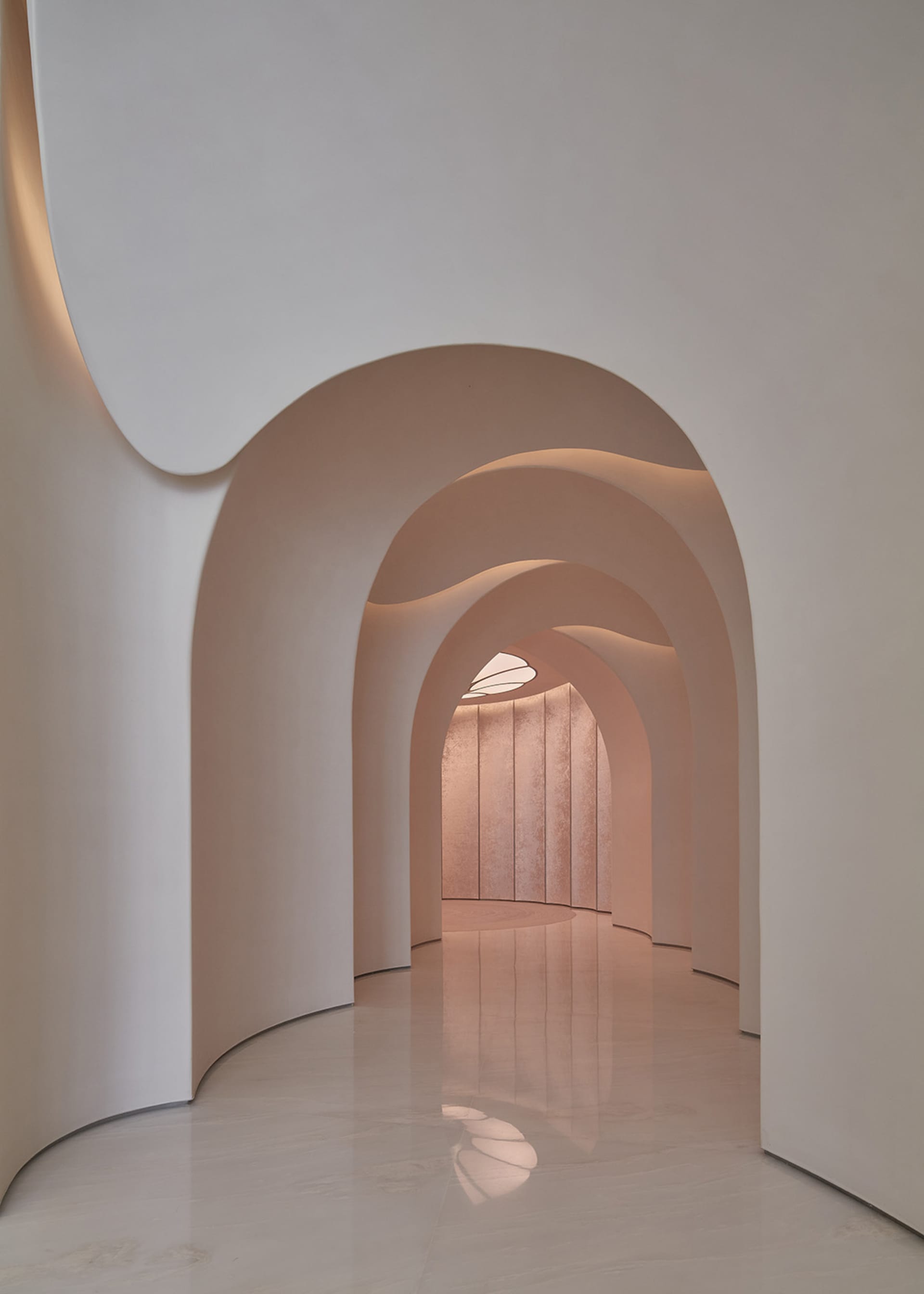 A soft pink hallway with marble flooring, pink accents on the walls, and soft diffused lighting