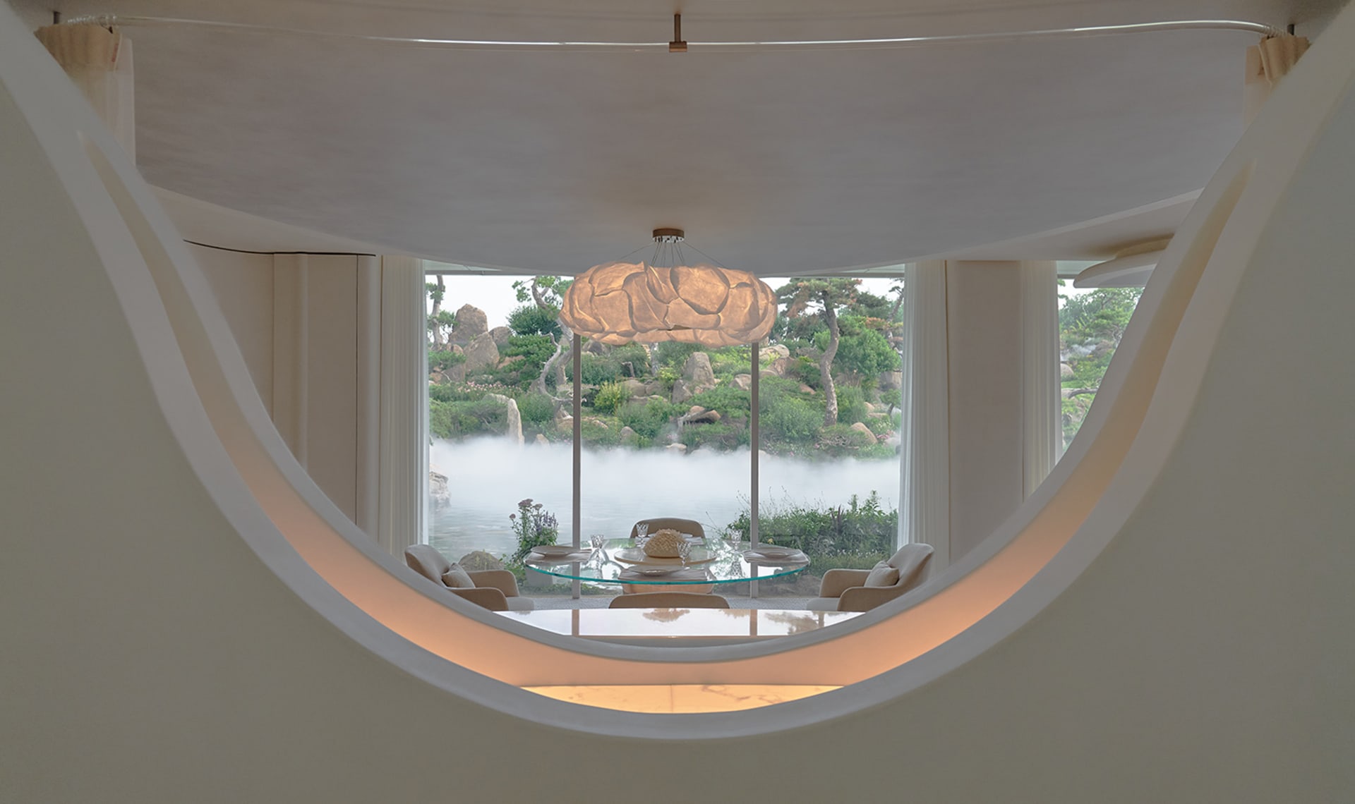 Bright and inviting living space with modern design, white walls, a glass dining table, and natural light from a large round window