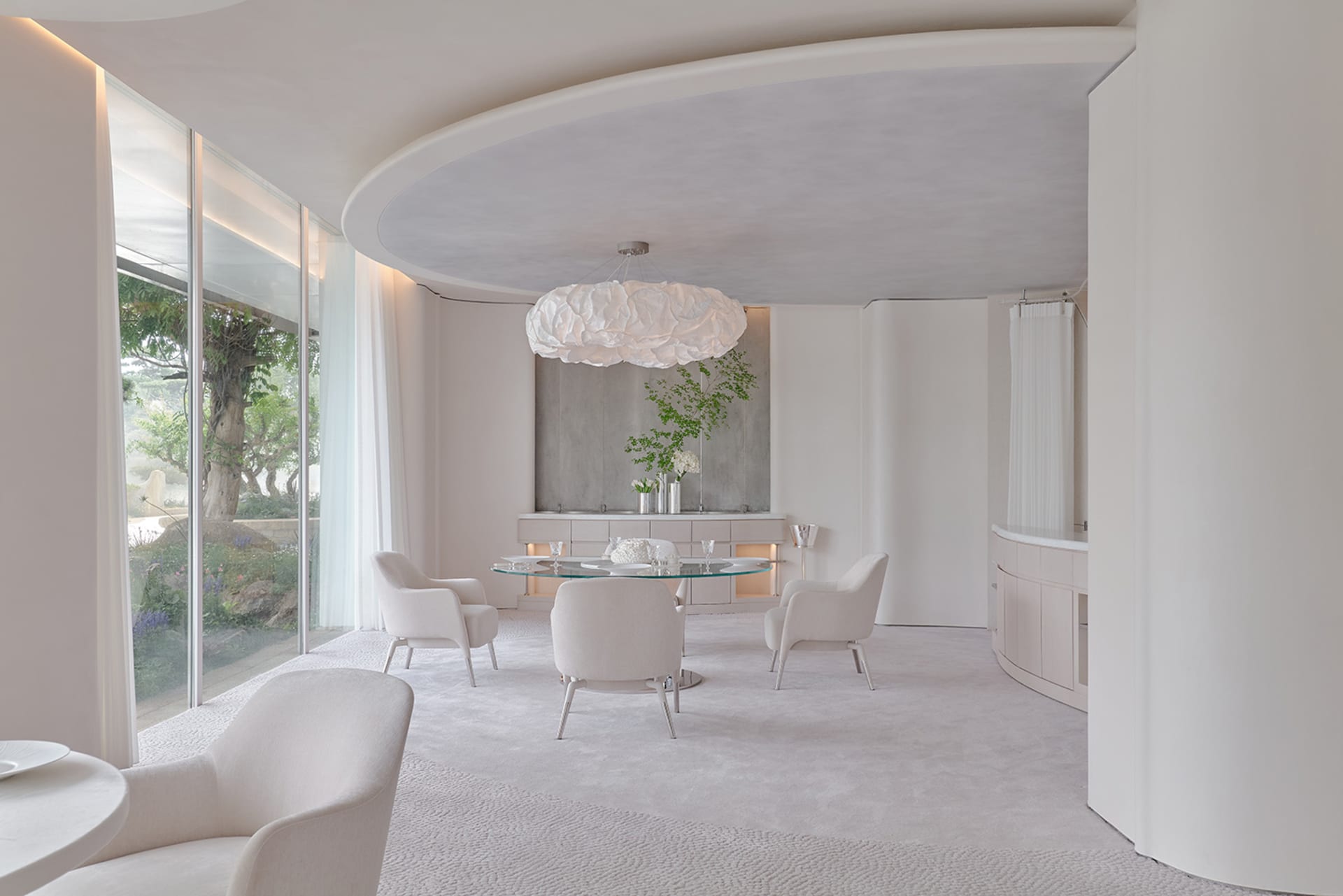 Modern open plan dining area with a glass table surrounded by chairs, a potted plant, and a modern atmosphere