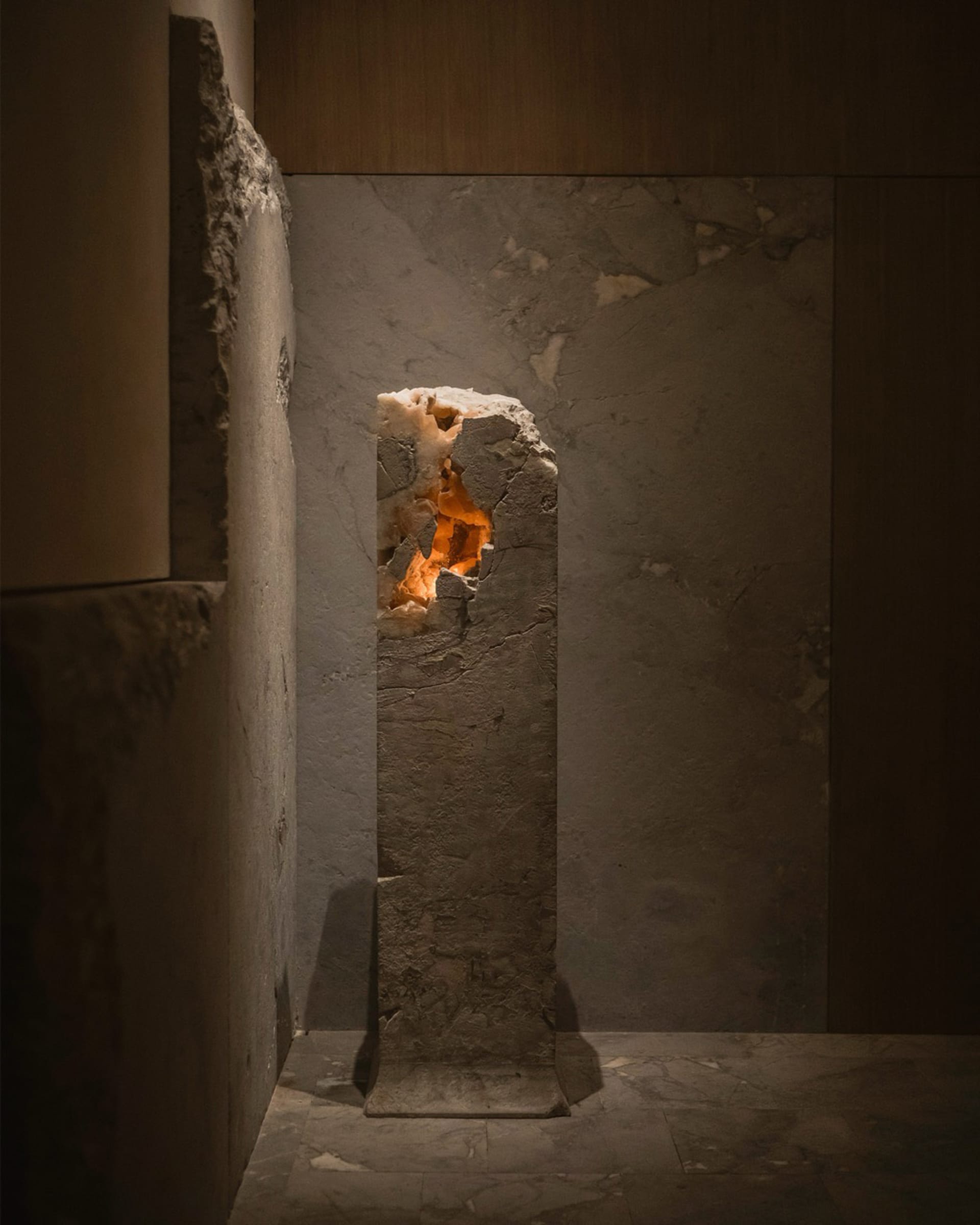 A rustic interior space with a stone wall featuring a hole that could be a window or an opening, with a cozy atmosphere