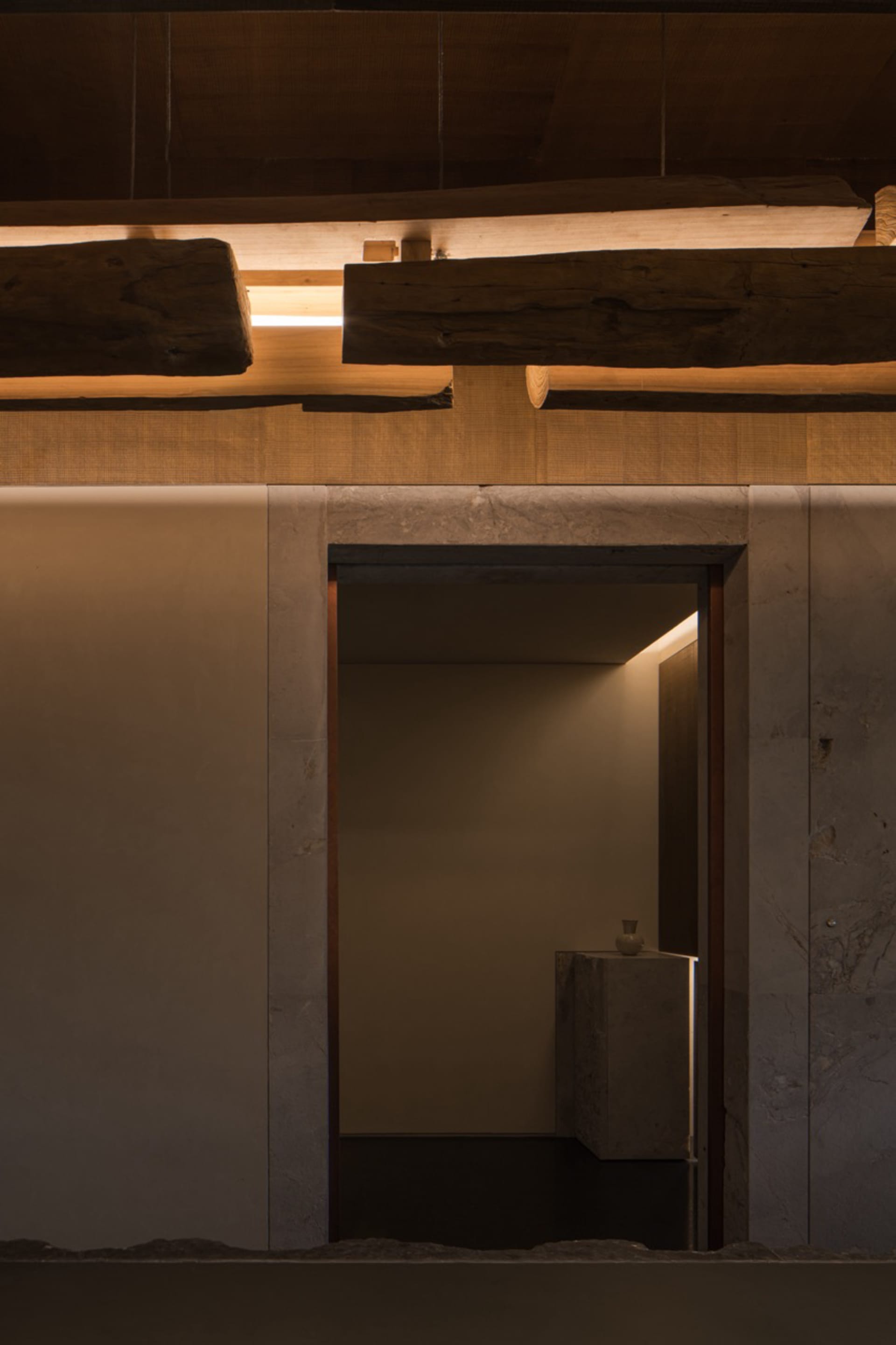 A modern bathroom with two sinks, stone walls, and a doorway leading to another room