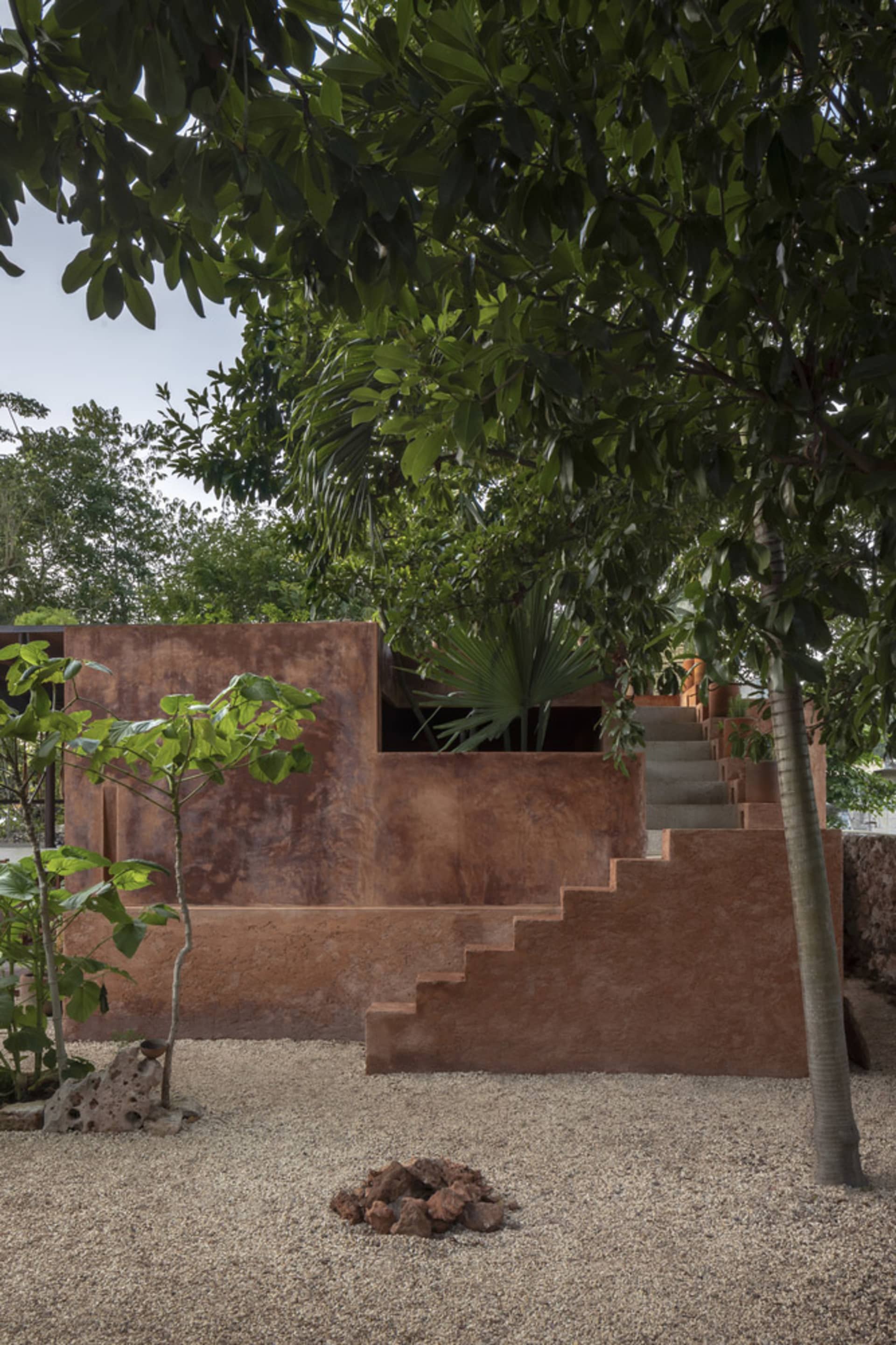 A serene outdoor area with a staircase, potted plants, and a bench, surrounded by natural scenery