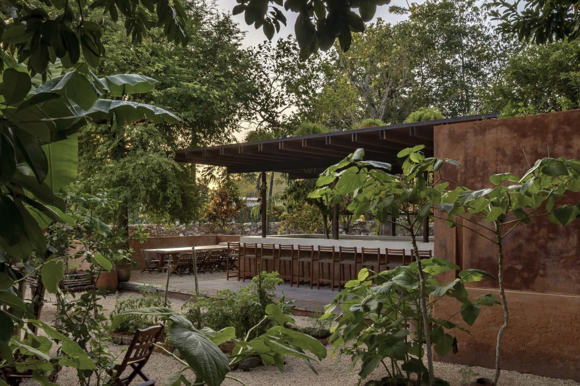 A covered outdoor dining area with a table and chairs, surrounded by a pleasant atmosphere