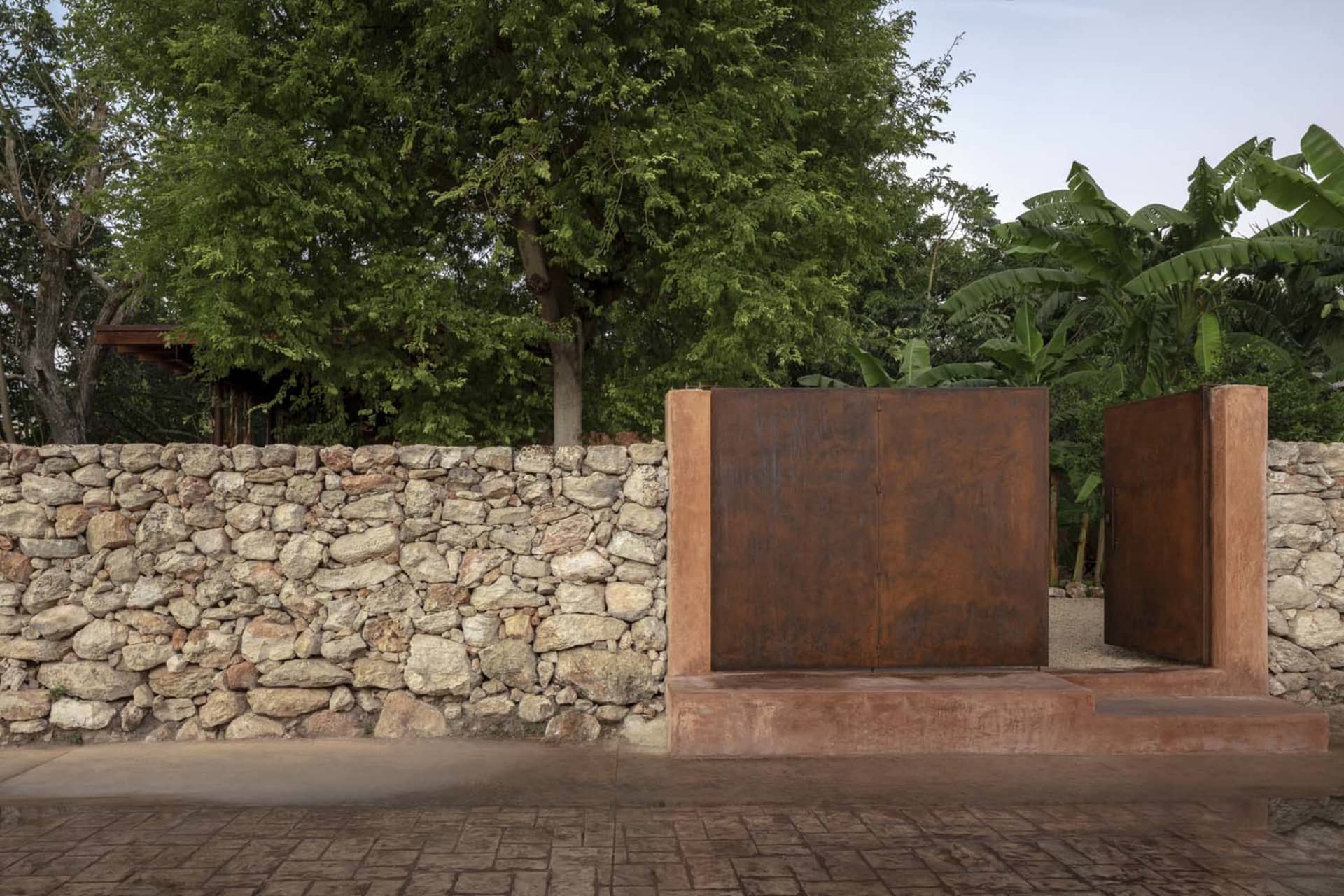 A rustic stone wall in front of a tree, with natural surroundings and a focus on the stone texture