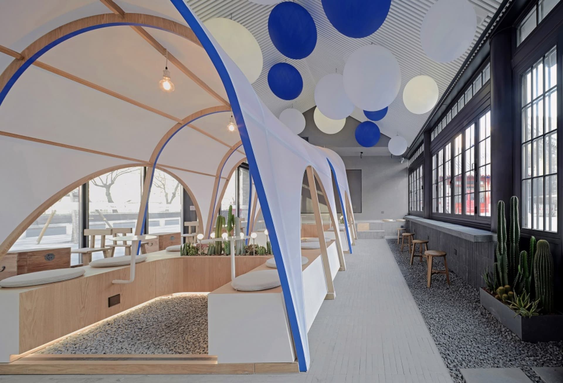 開放式餐廳內部，多張餐桌椅、盆栽植物，及天花板懸吊圓球