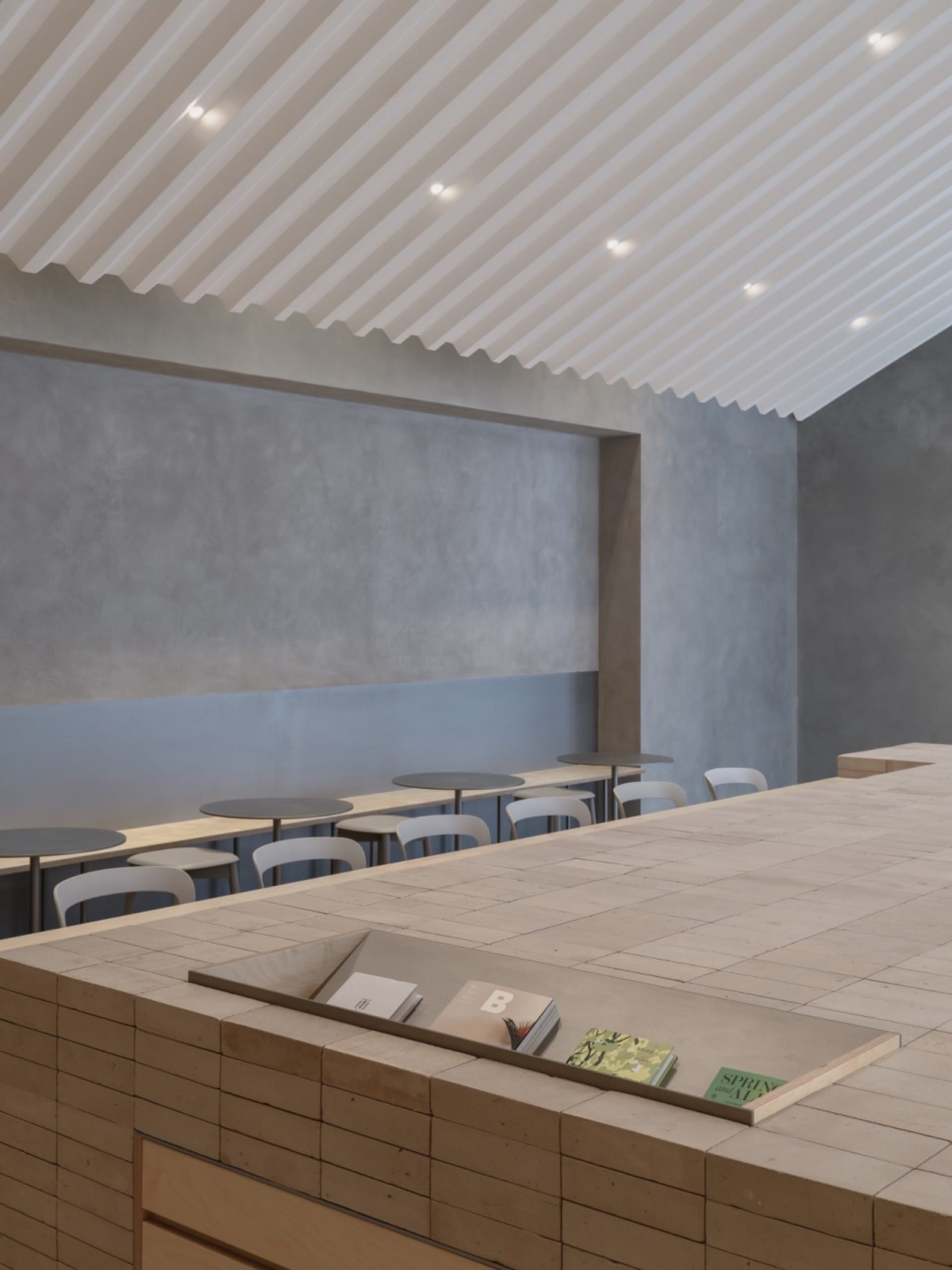 Cozy cafe interior with a counter and chairs, featuring a display of books and a warm atmosphere
