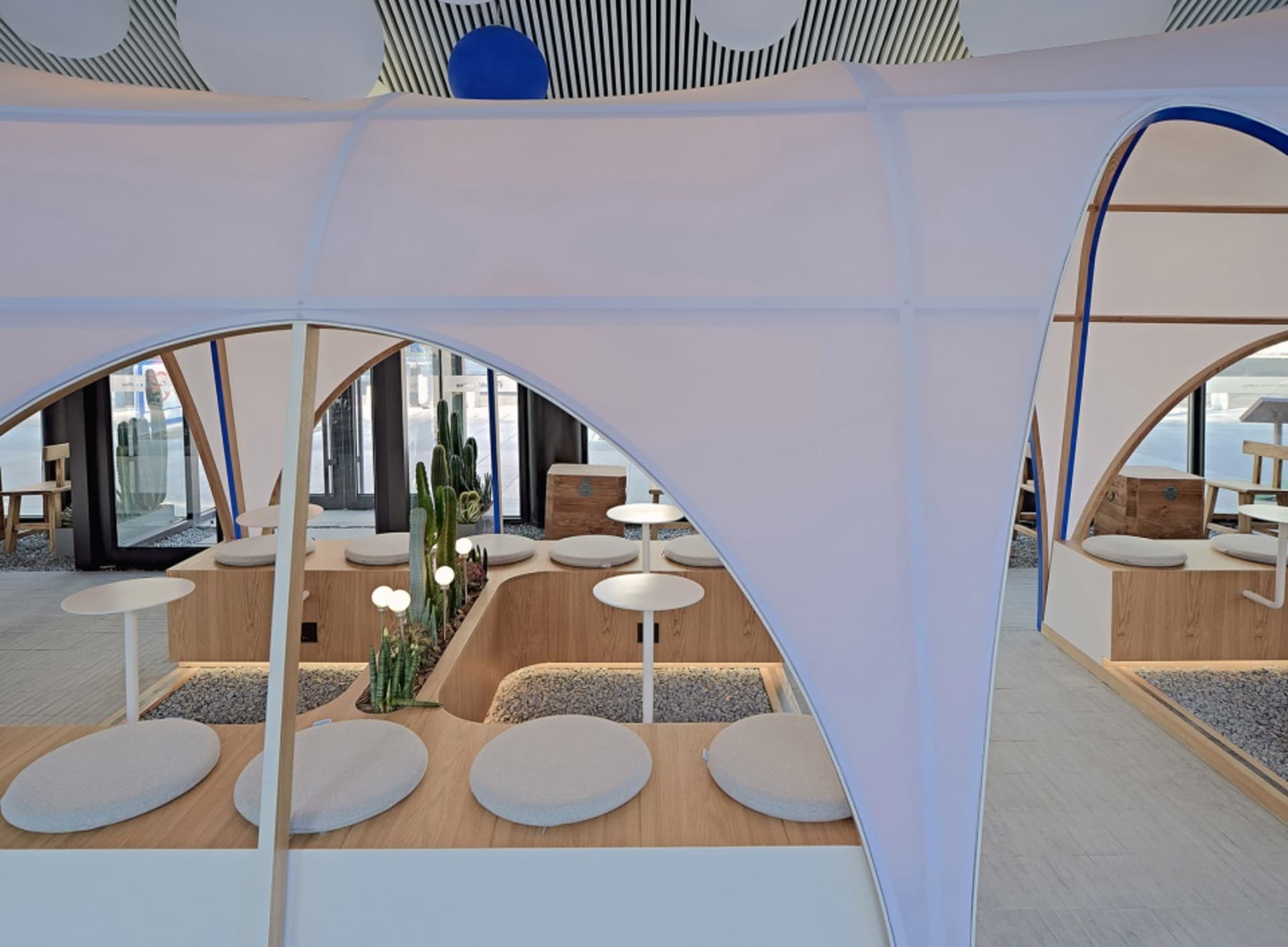 A cozy outdoor dining space with a white tent, cushioned chairs, and potted plants, creating a warm and inviting atmosphere