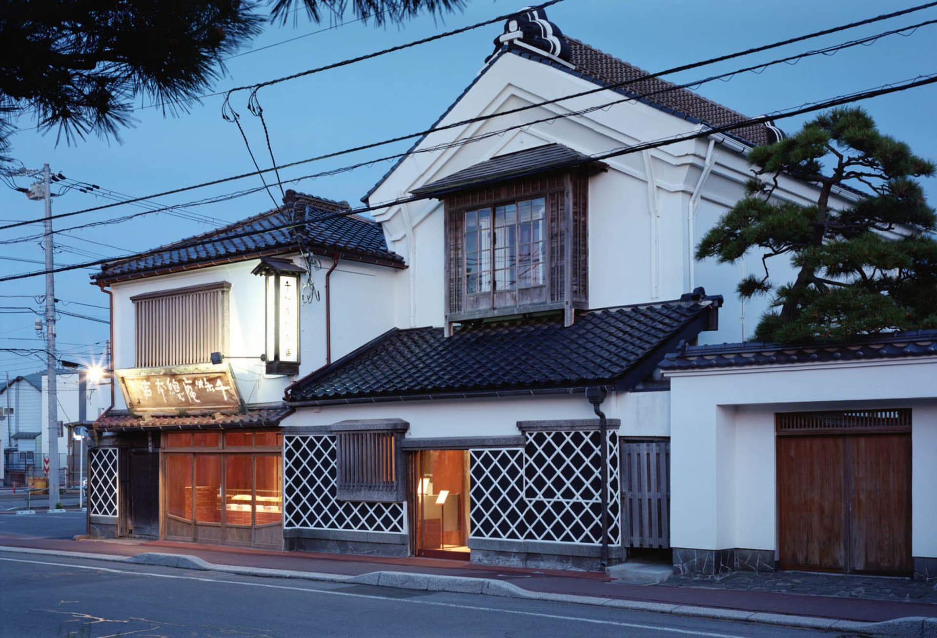 Exterior photo of a traditional Japanese house with a balcony, window, and outdoor furniture in a serene environment