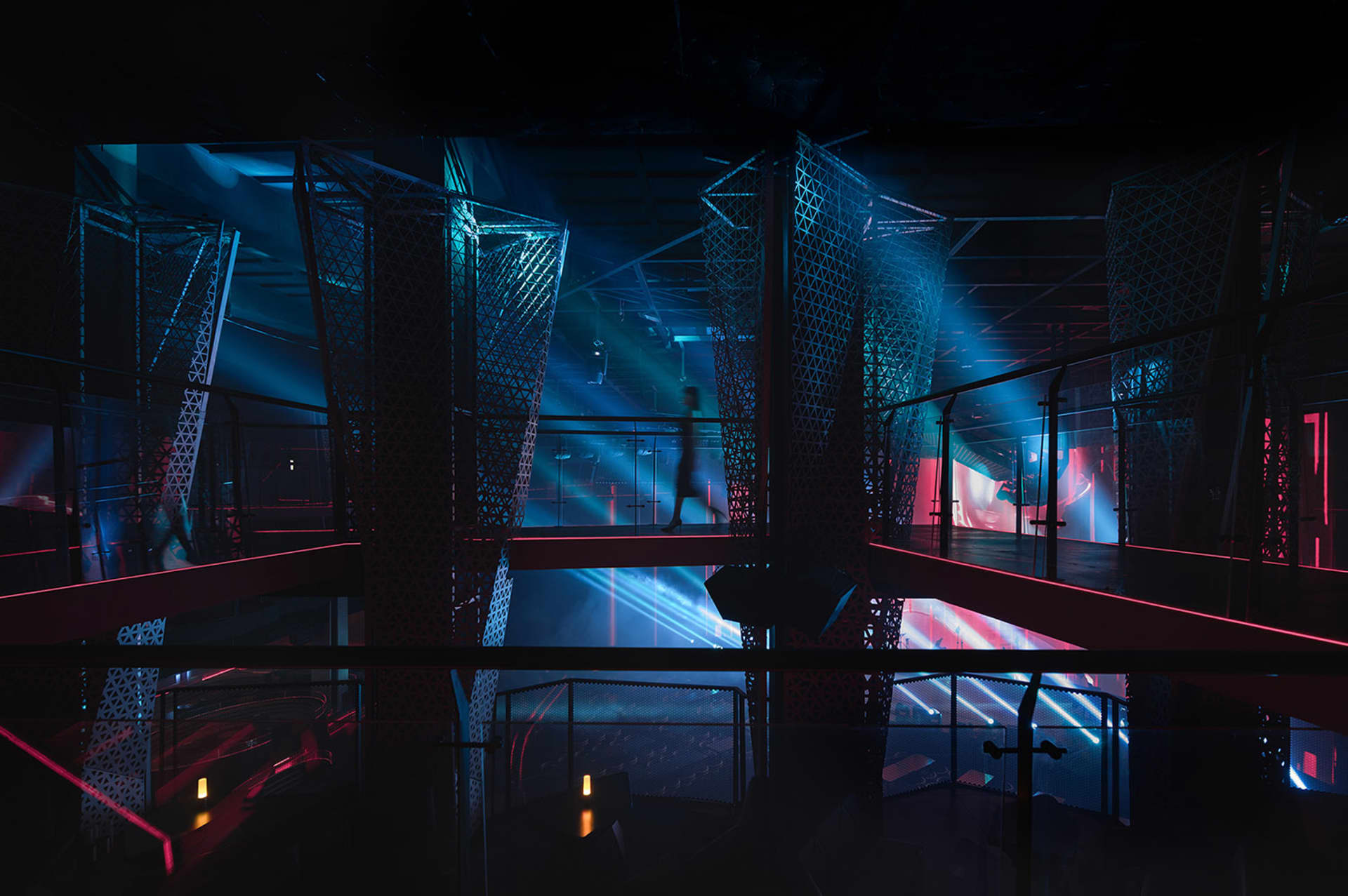 A bustling indoor space with a large red structure in the center, surrounded by people walking and engaging in various activities