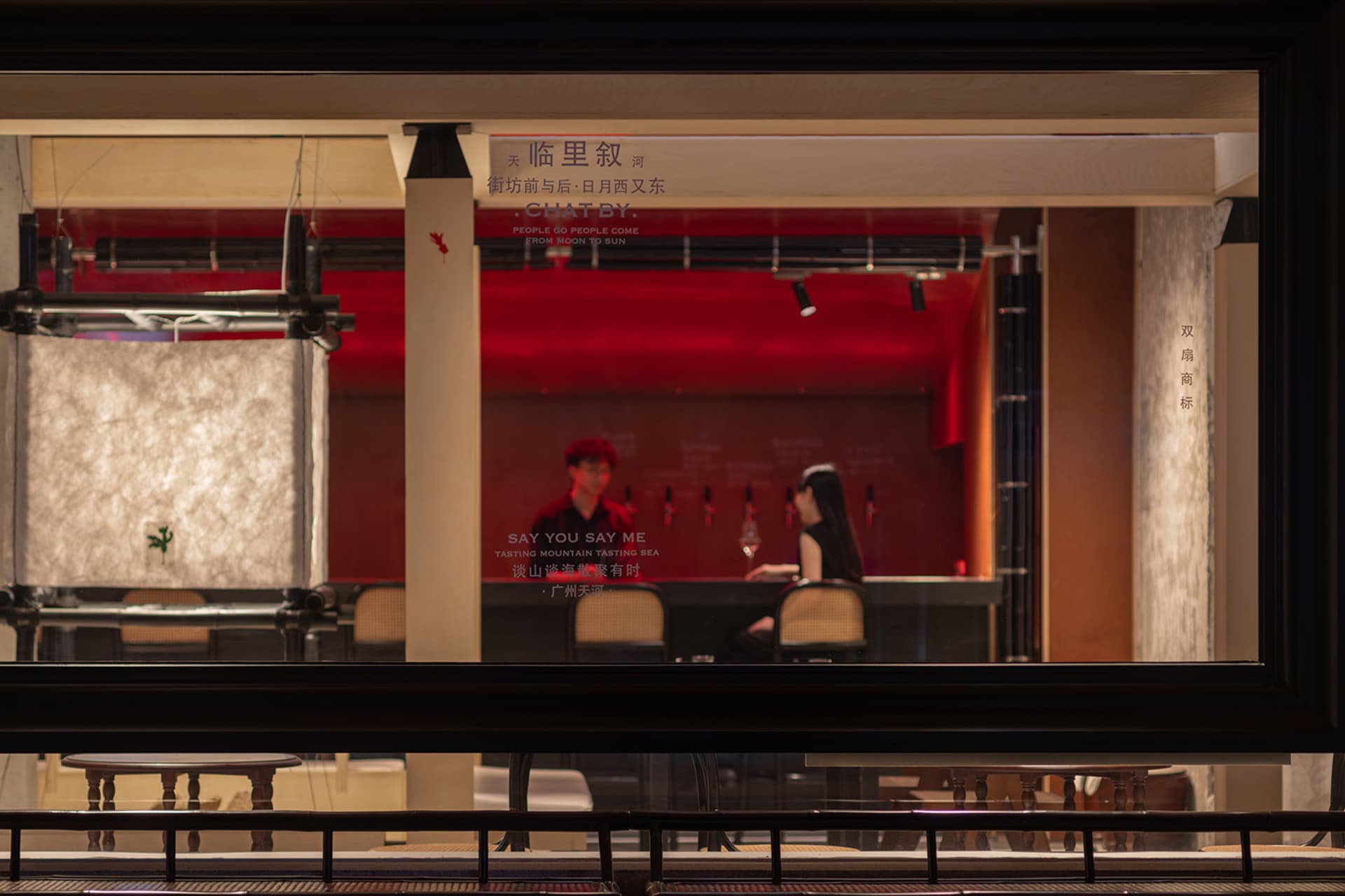 現代設計的休閒酒吧場景，特色為紅色重點牆、吧台與座椅，顧客享用飲料並暢聊