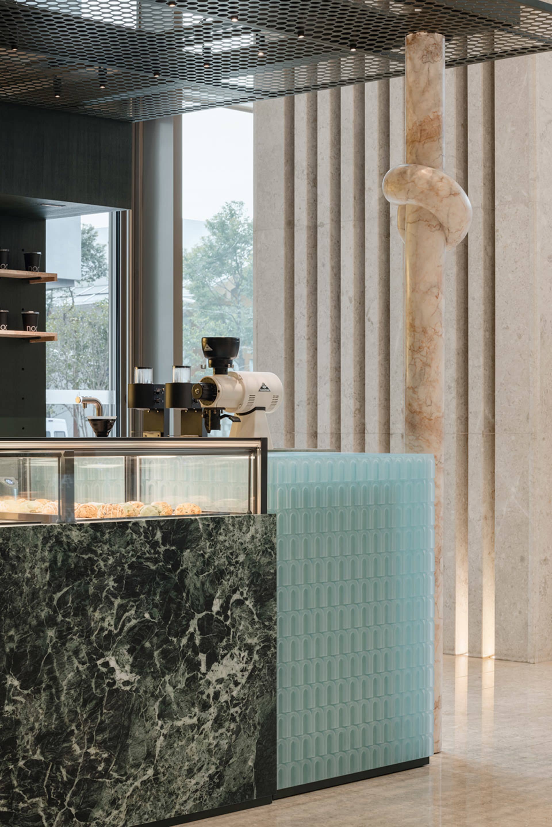 A well-organized coffee shop with a marble countertop, display case, and modern appliances