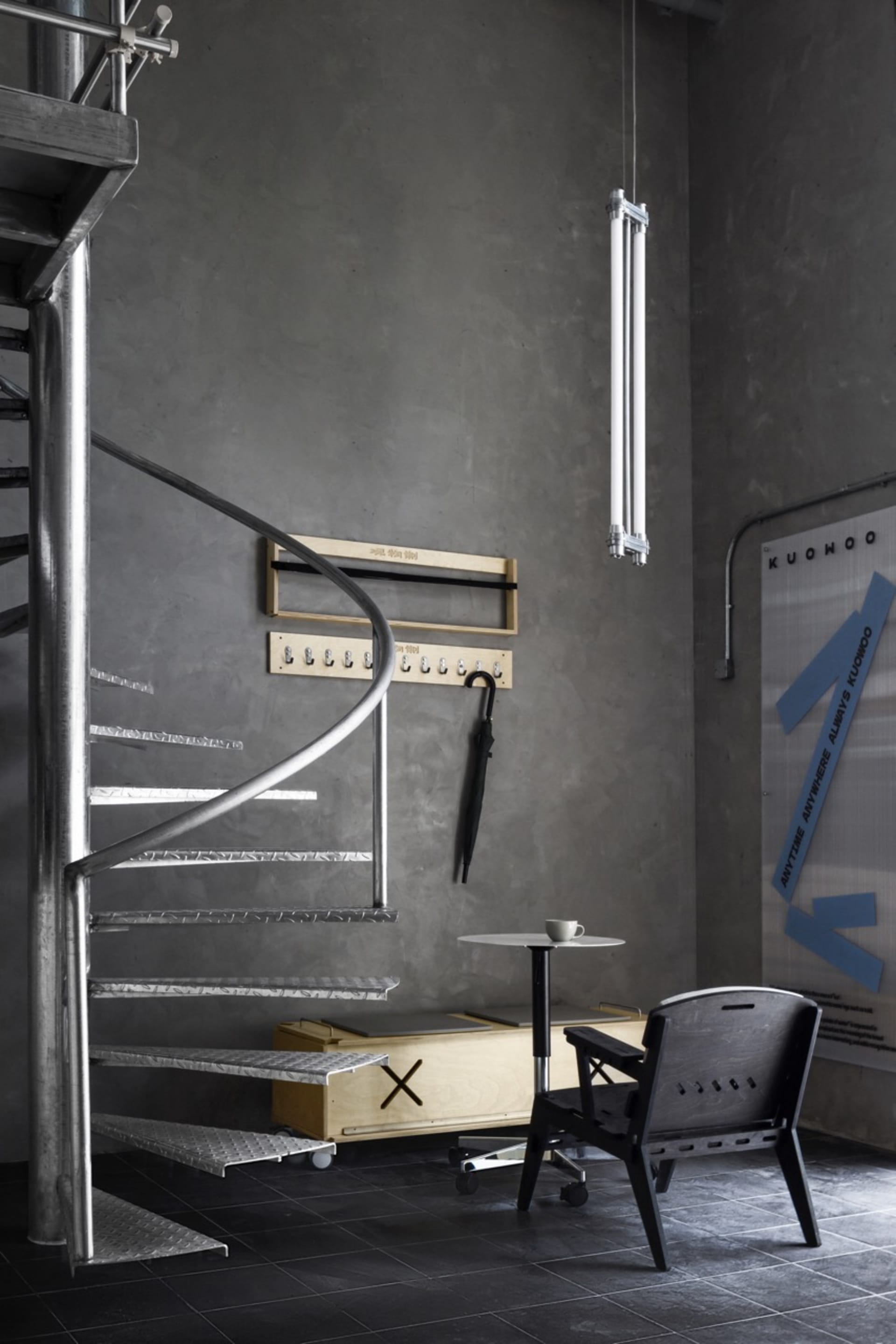 Modern living space with metal staircase, a chair, and a dining table in a contemporary and stylish environment