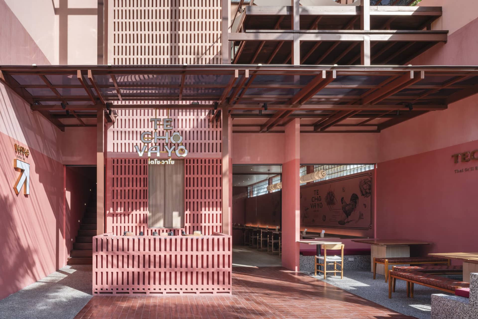 Cozy modern restaurant with pink walls, a large window, and chairs around a dining table