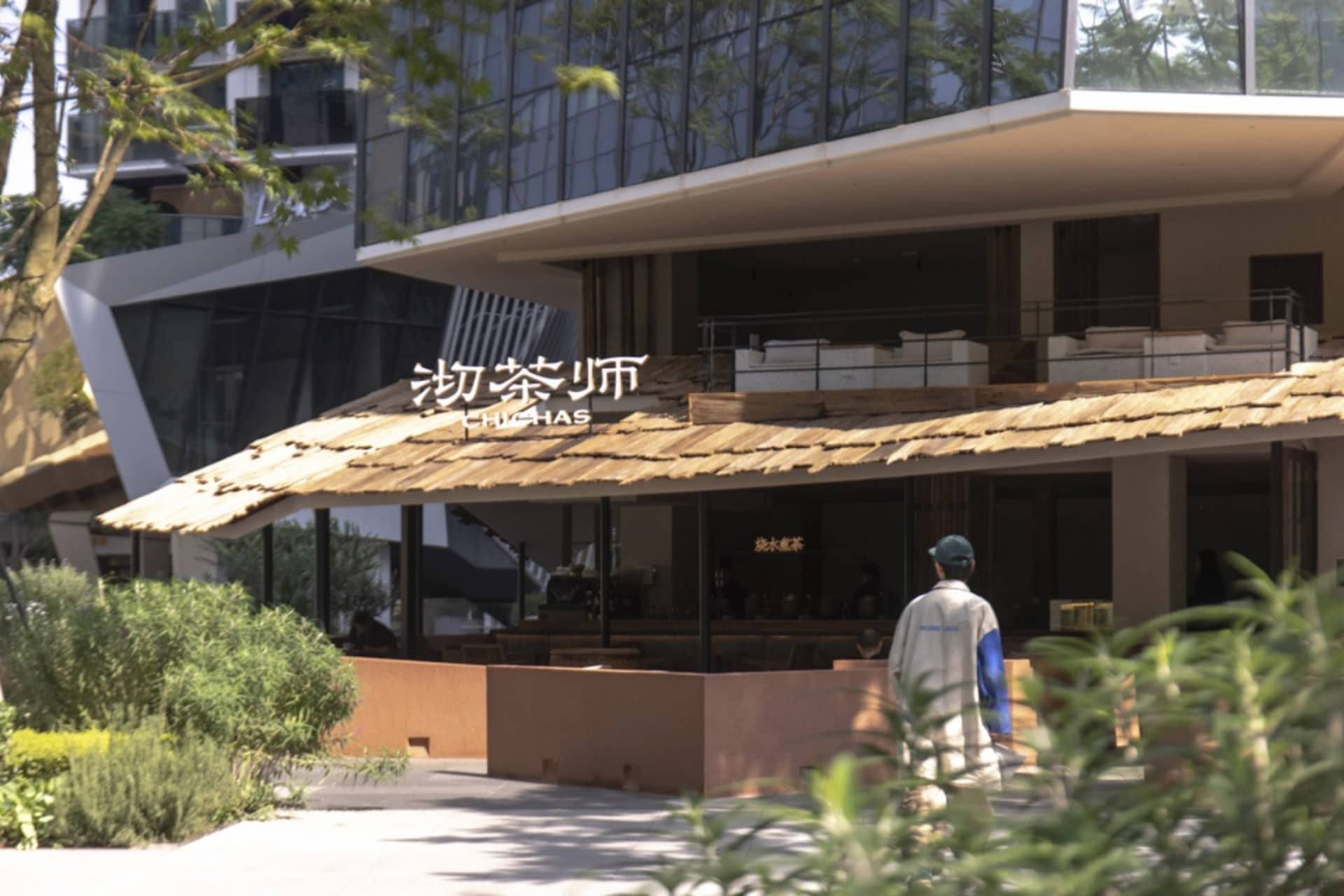 木質屋頂與大型招牌的亞洲餐廳，內有桌椅，多人正在用餐享樂