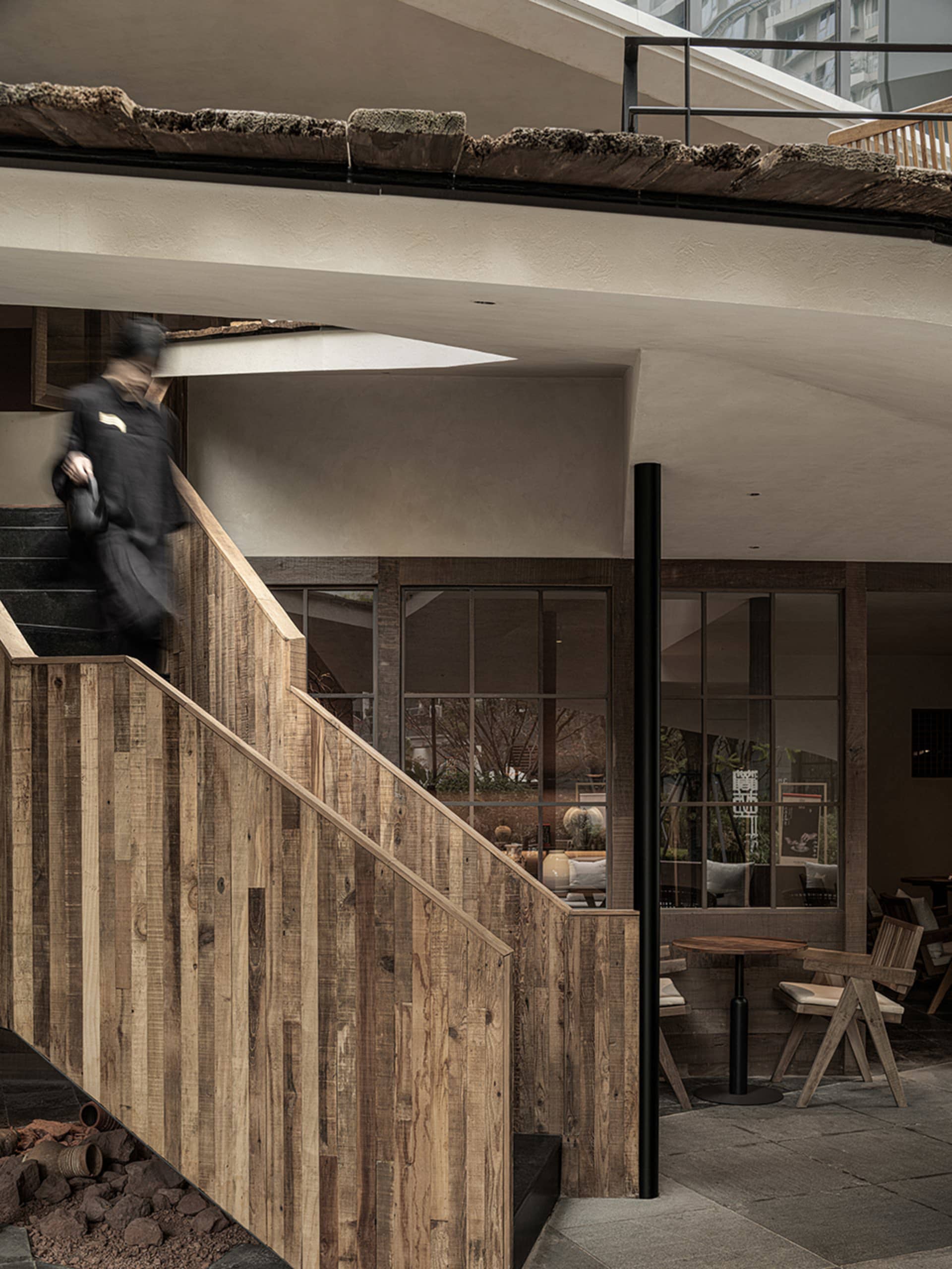 A warm and inviting staircase in a restaurant with a wooden railing and a person walking up the stairs