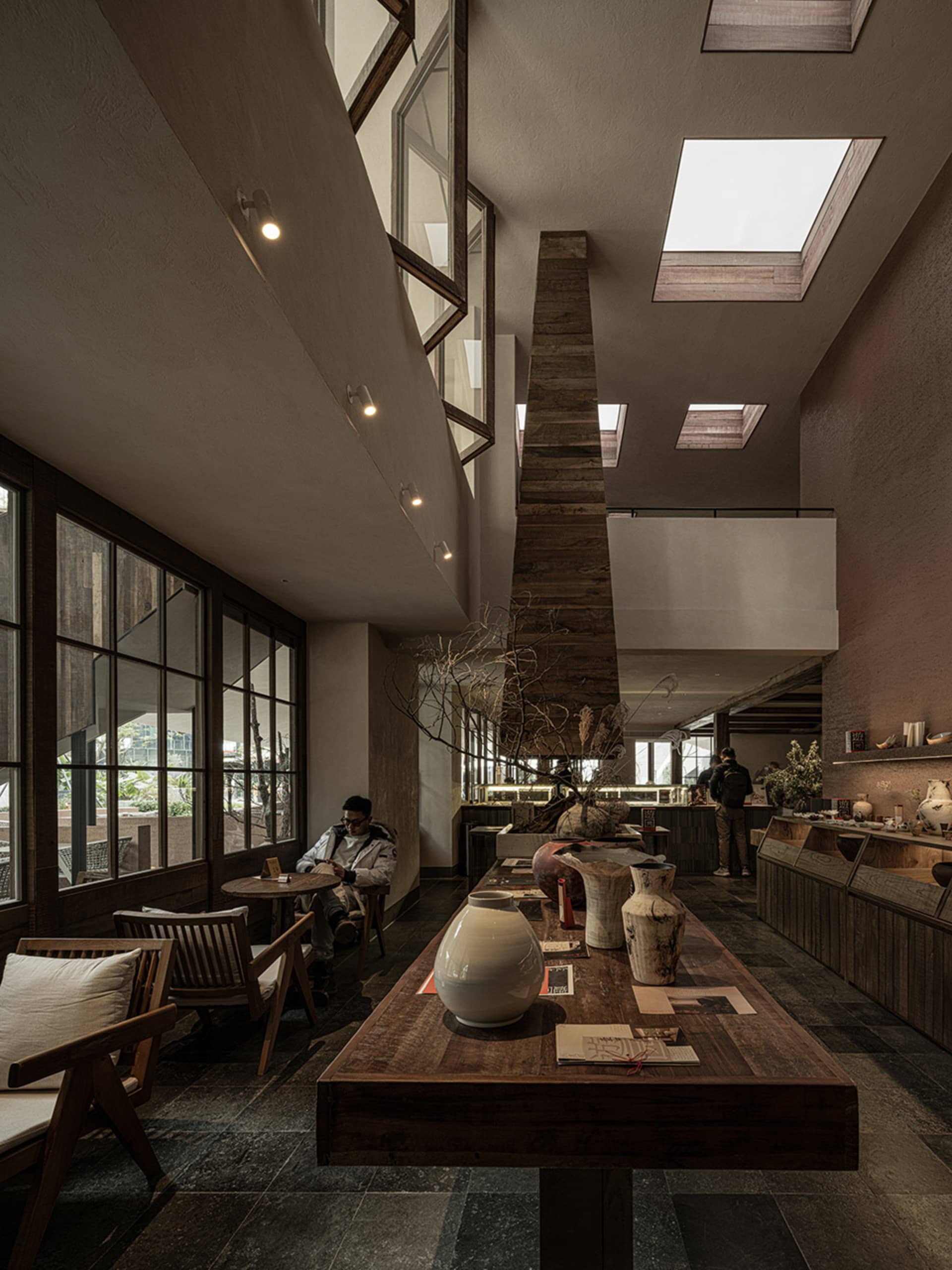 Cozy modern dining space with wooden feature, multiple tables, chairs, and dim lighting