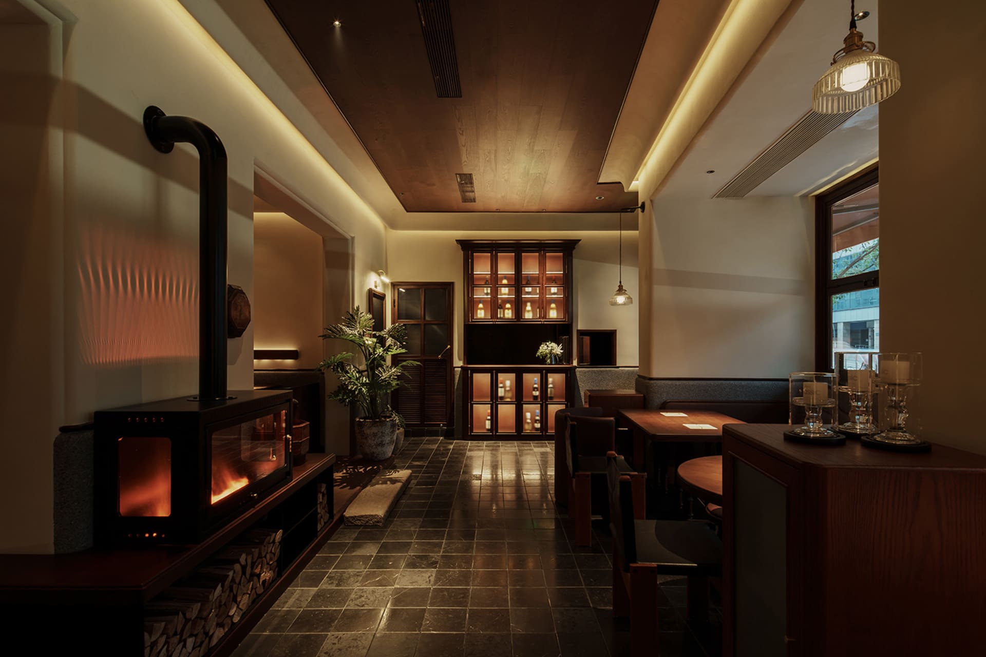 Elegant dining space with modern furniture, potted plants, and a fireplace, creating a warm and inviting atmosphere