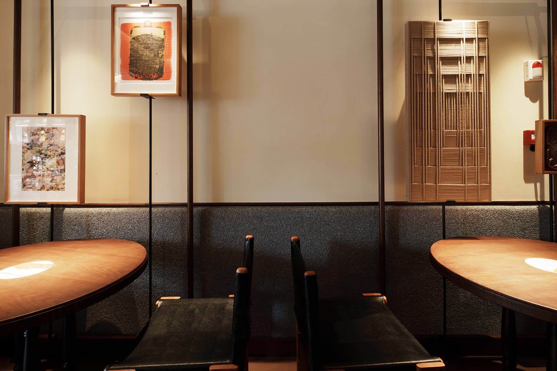 A symmetrical dining space with two chairs at opposite ends of a table, a nearby couch, and warm brown and white walls