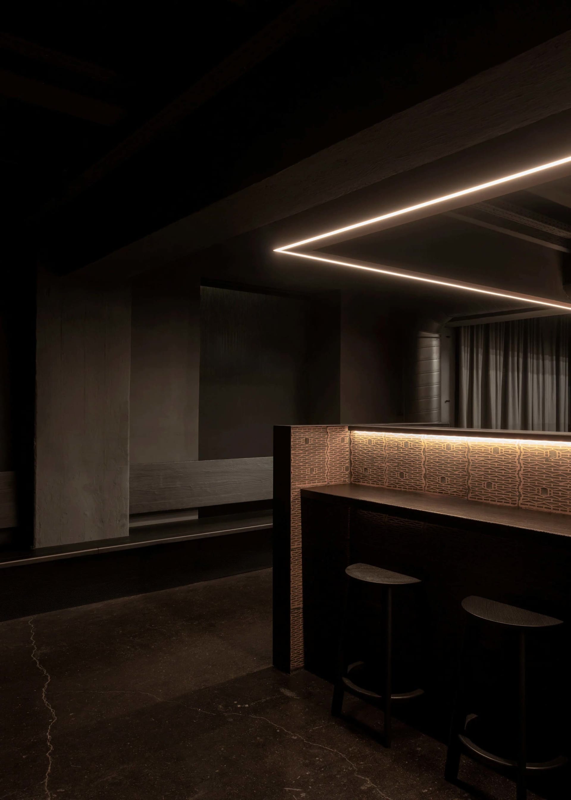 Intimate bar area with stools and a couch in a darkened environment