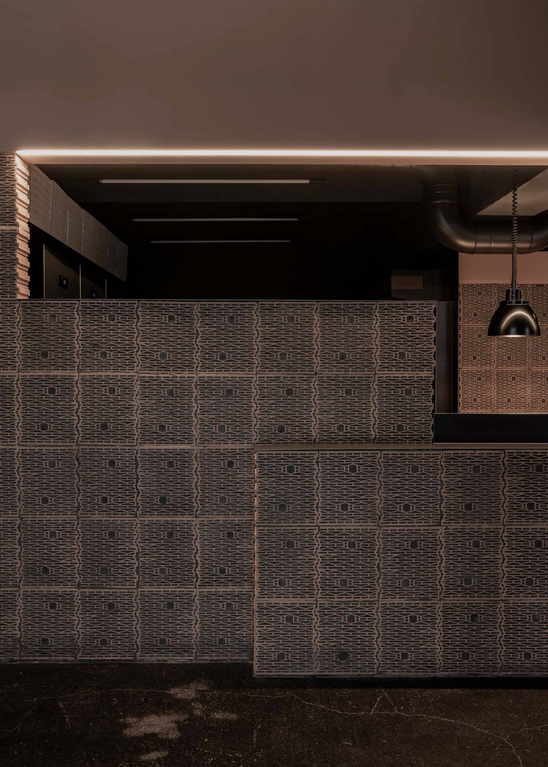 Warm and inviting room with a wooden panelled wall featuring a unique pattern, illuminated by two lights on either side