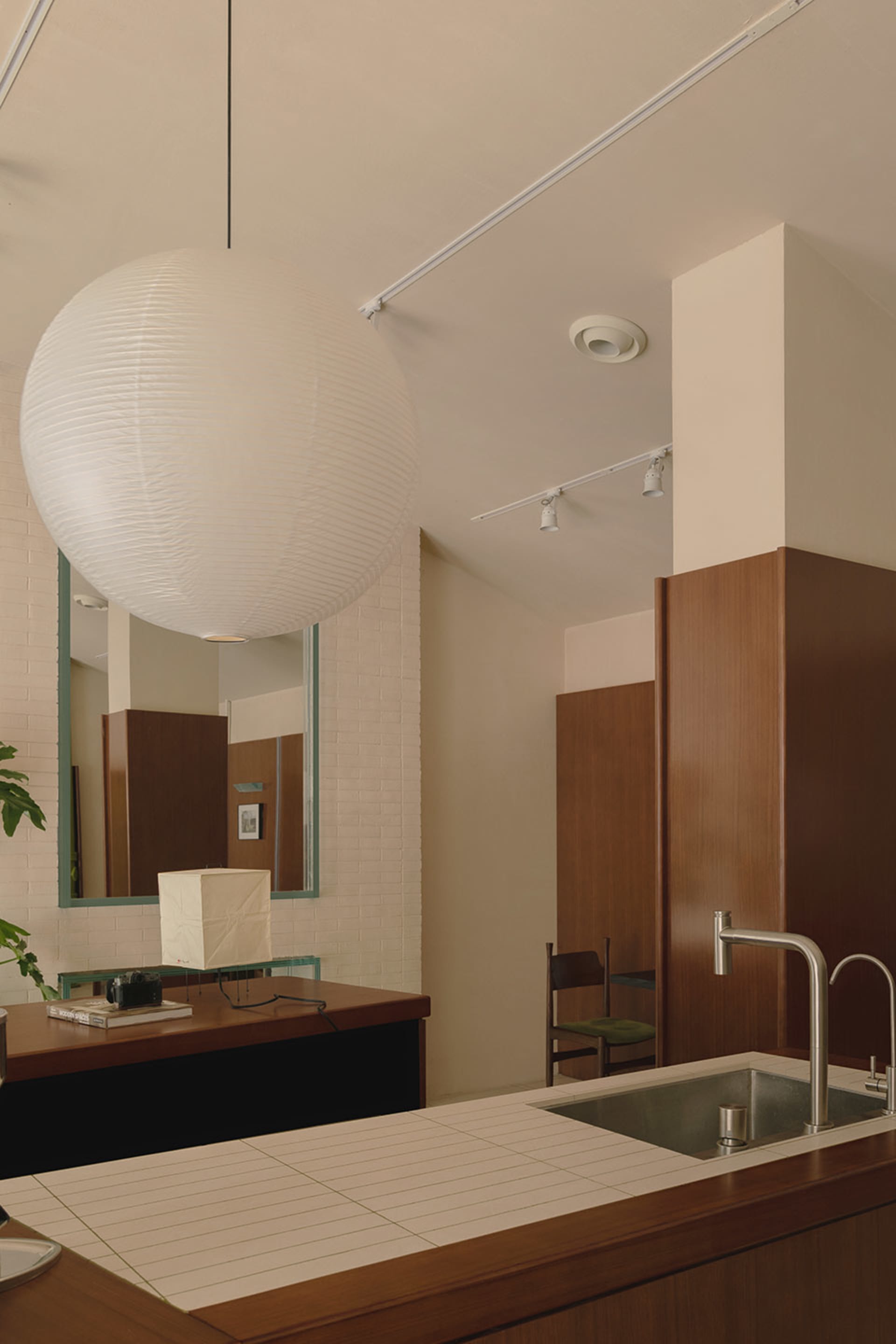 Modern bathroom with a sink, mirror, and a large white ball hanging from the ceiling, accompanied by two chairs and a minimalist design