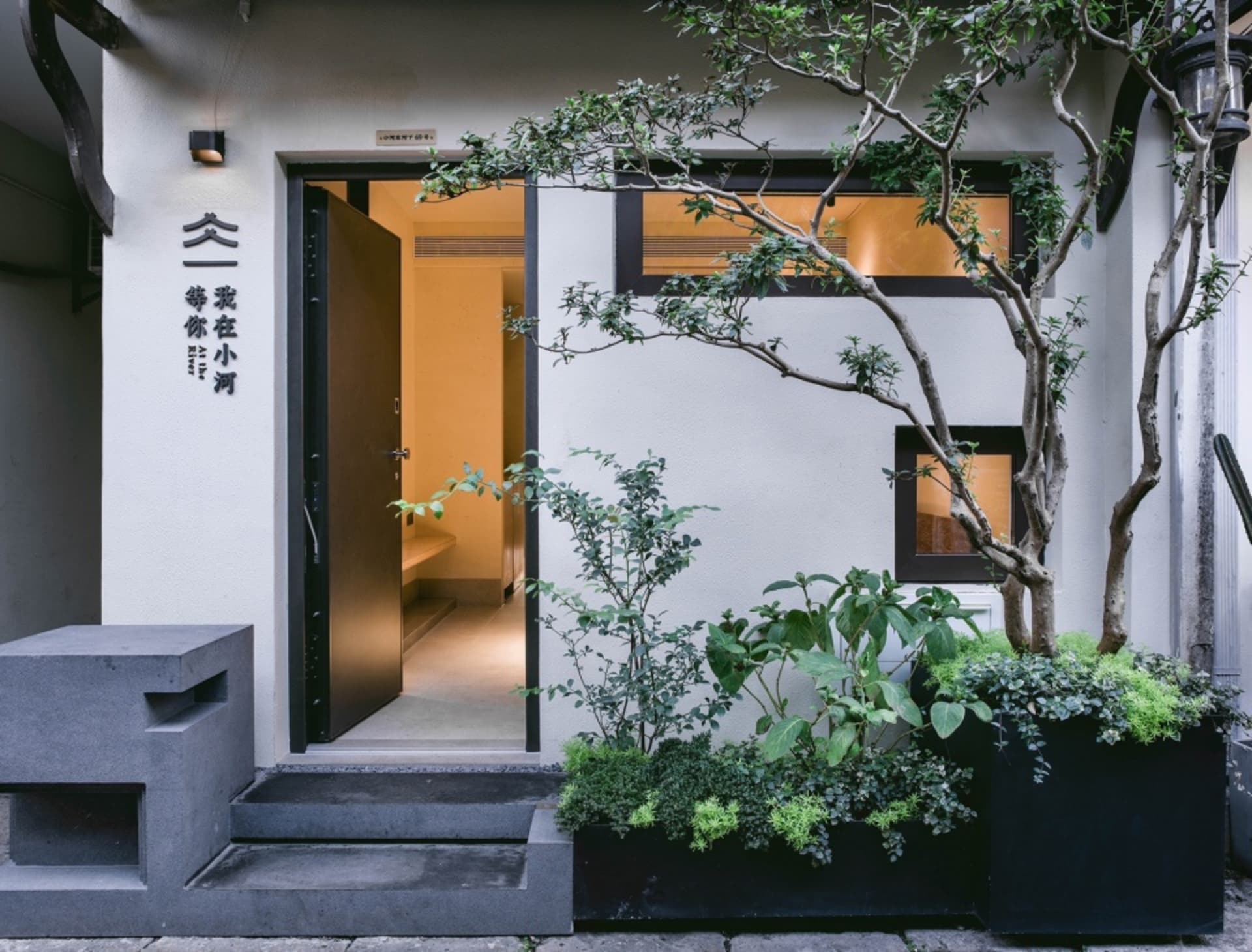 寧靜亞風住宅，配有小庭園與盆栽，潔白外牆及門楣上方招牌