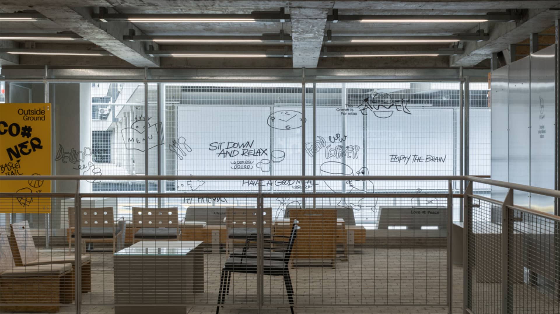 Modern restaurant with wood and glass elements, chairs, and a large window allowing natural light
