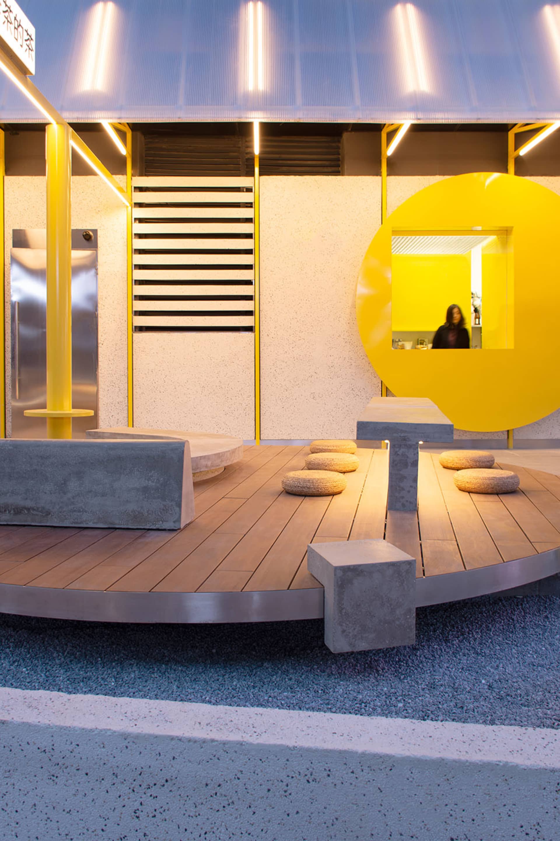 A modern public space with a circular design, featuring yellow walls, benches, and a warm atmosphere
